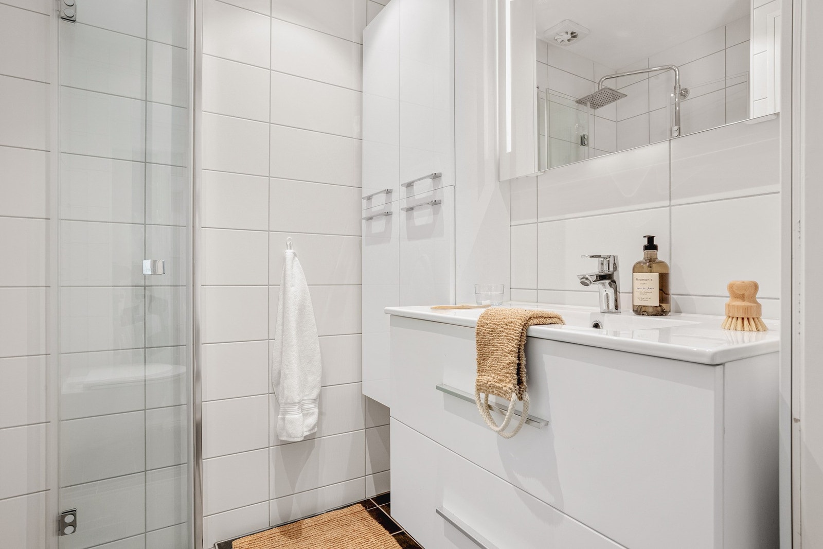 Badet er innredet med vegghengt toalett, servant med innredning, og dusjhjørne. Galleribilde