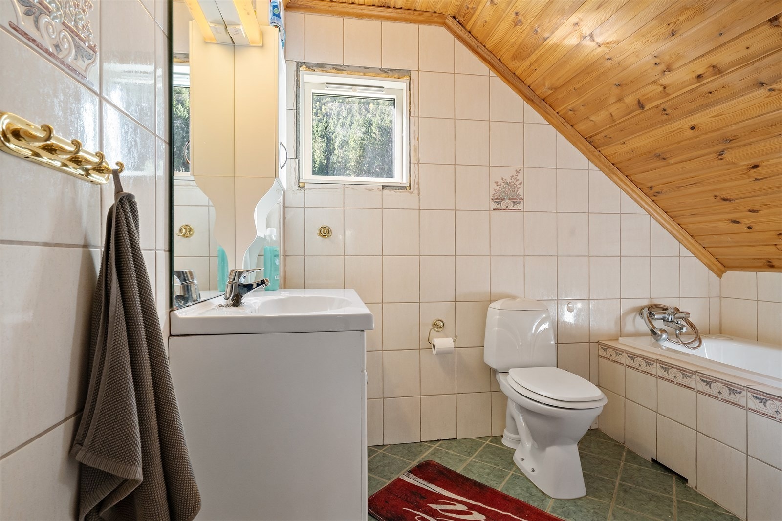 Bad på loft med flislagt gulv med varmekabler . Innredet med servant, toalett og innebygd badekar. Galleribilde