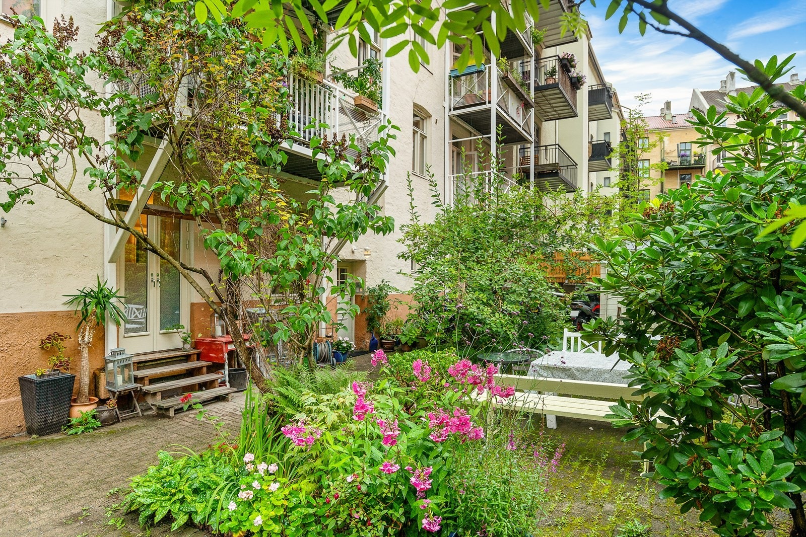 Bakgården er pent beplantet og har hellelagte internveier Galleribilde