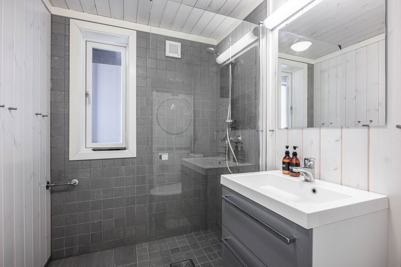 Stilrent bad med rene linjer, dusjhjørne og elegant servant. Galleribilde