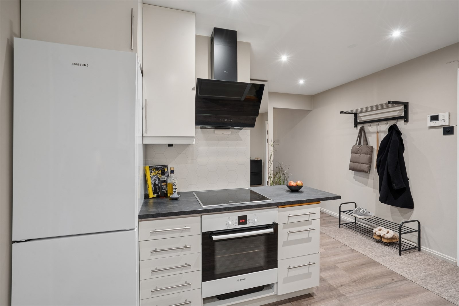 Kjøkkenet har glatte, hvite fronter og benkeplate i laminat. Det er utstyrt med nedfelt stålkum og ettgreps kjøkkenkran. Galleribilde