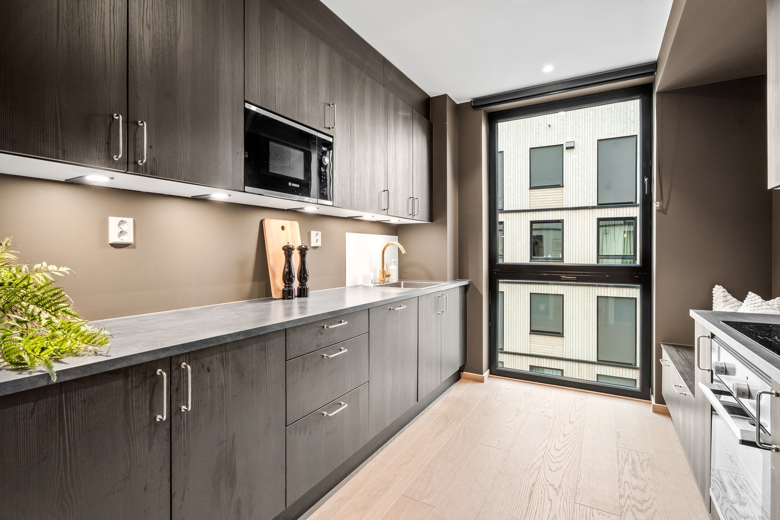 Adskilt kjøkken med glatte fronter, laminatbenkeplate og integrerte hvitevarer for en helhetlig og moderne stil. Galleribilde