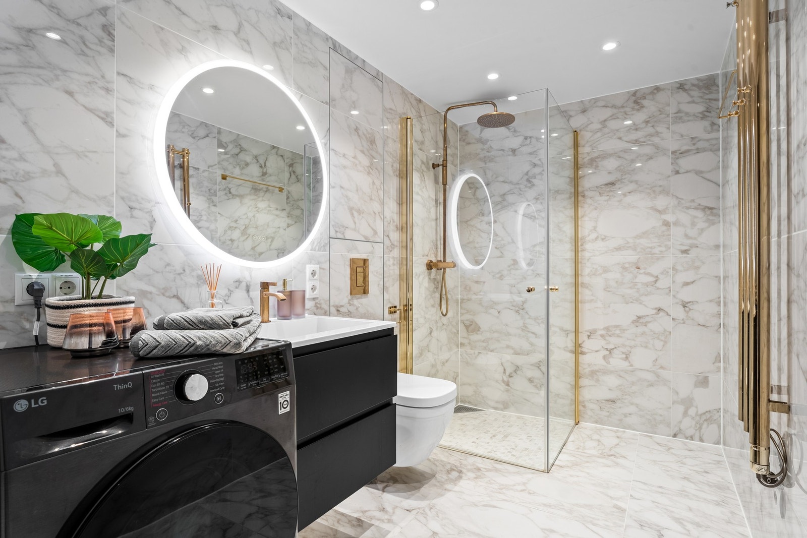 Flislagt bad med vannbåren gulvvarme. Innredningen består av heldekkende servant med skap, stort rundt speil med lysarmatur og veggmontert klosett. Galleribilde