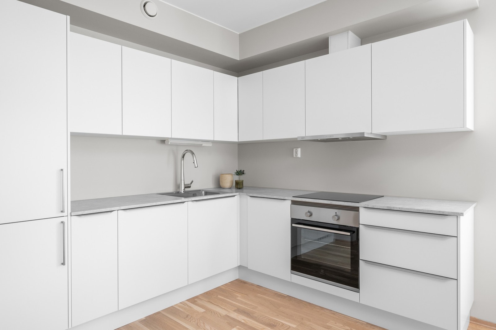 Romslig og moderne kjøkken med hvite fronter og mye skapplass. Integrert oppvaskmaskin, kjøleskap/frys og komfyr/stekeplate. Levert av Sigdal. Galleribilde