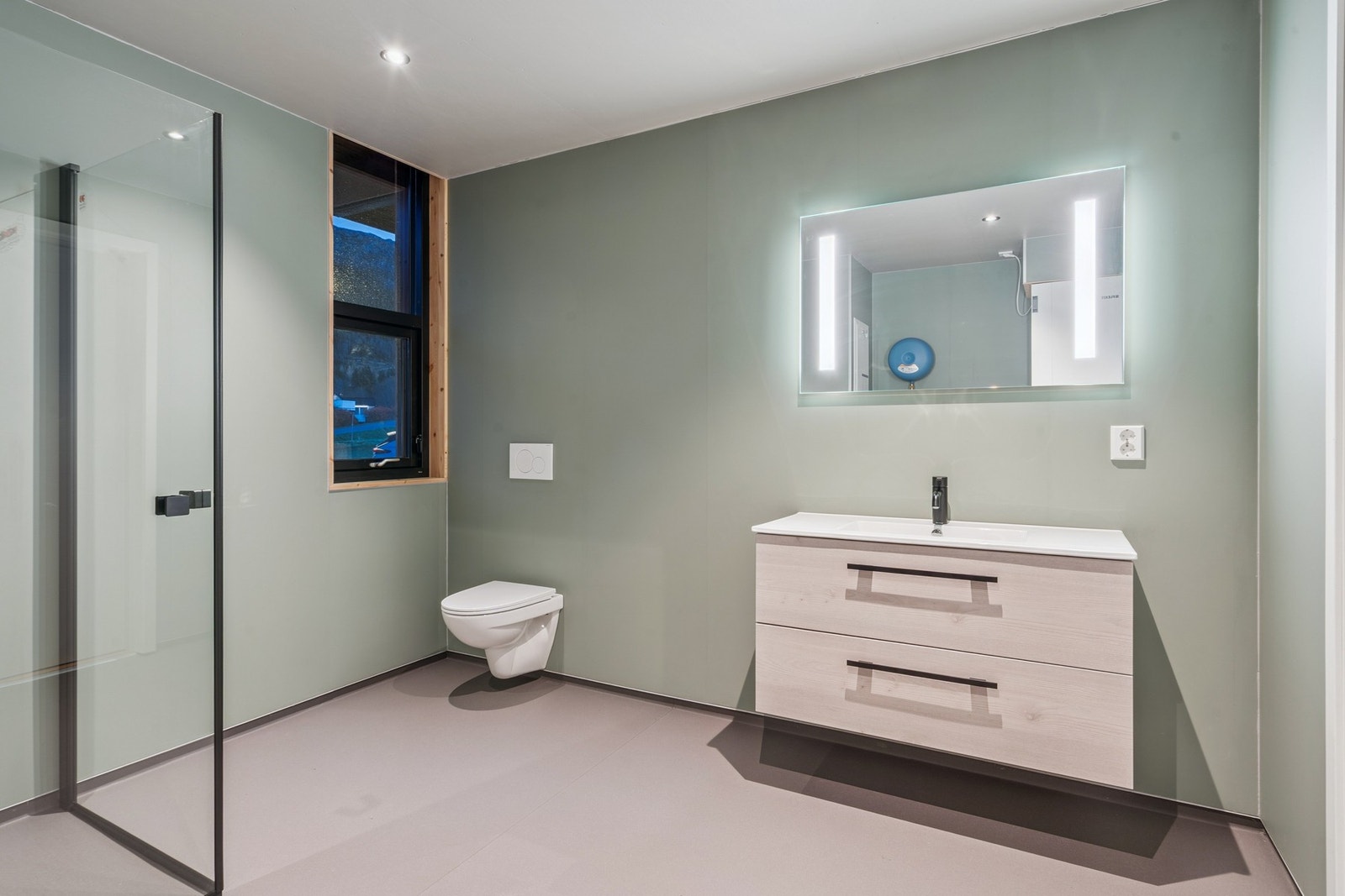 Badet er innredet med nedfelt servant, veggmontert toalett og et dusjhjørne Galleribilde