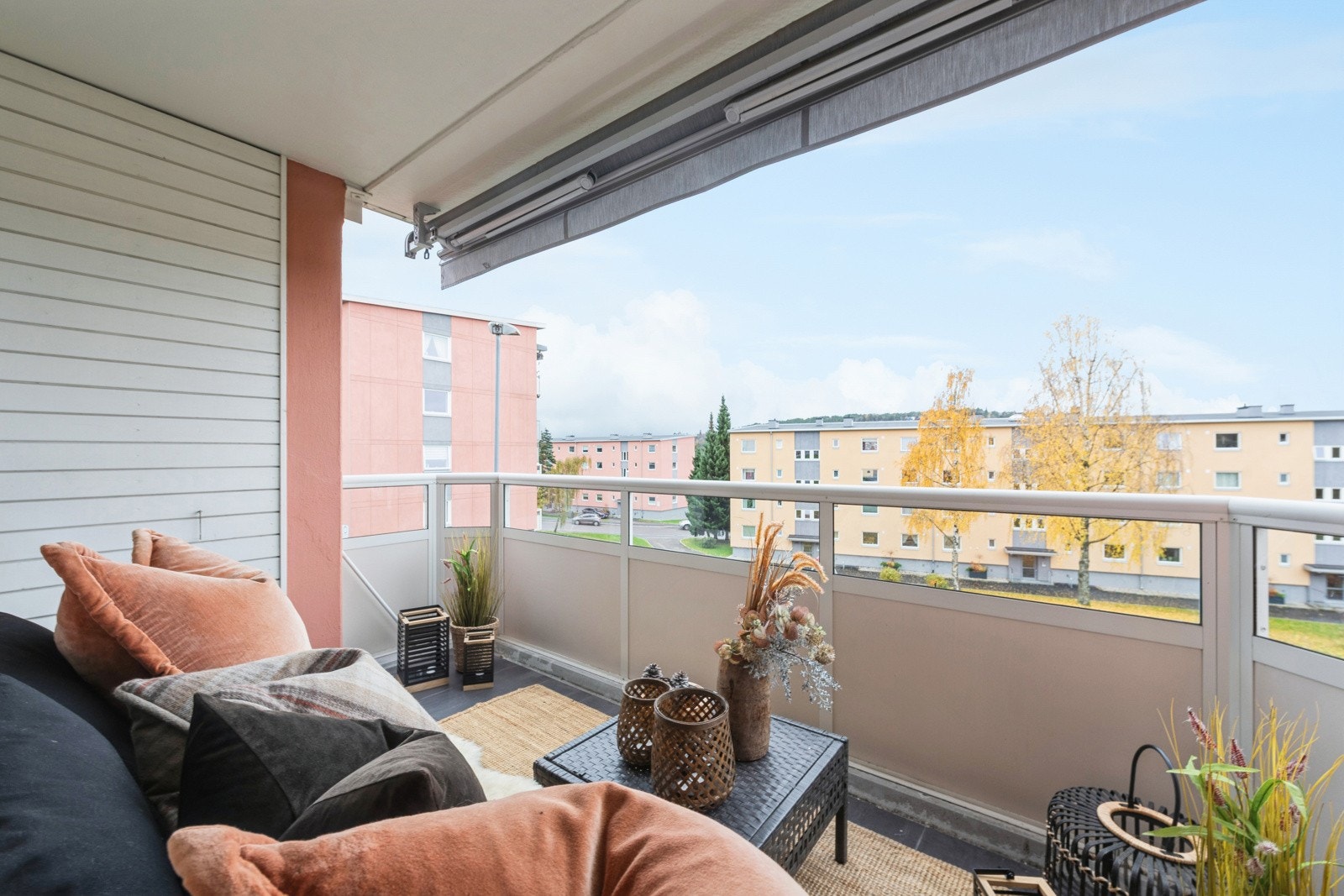 Balkong med fliser på gulv og markise som solskjerming. I tillegg er det utebelysning og strømuttak på vegg. Galleribilde
