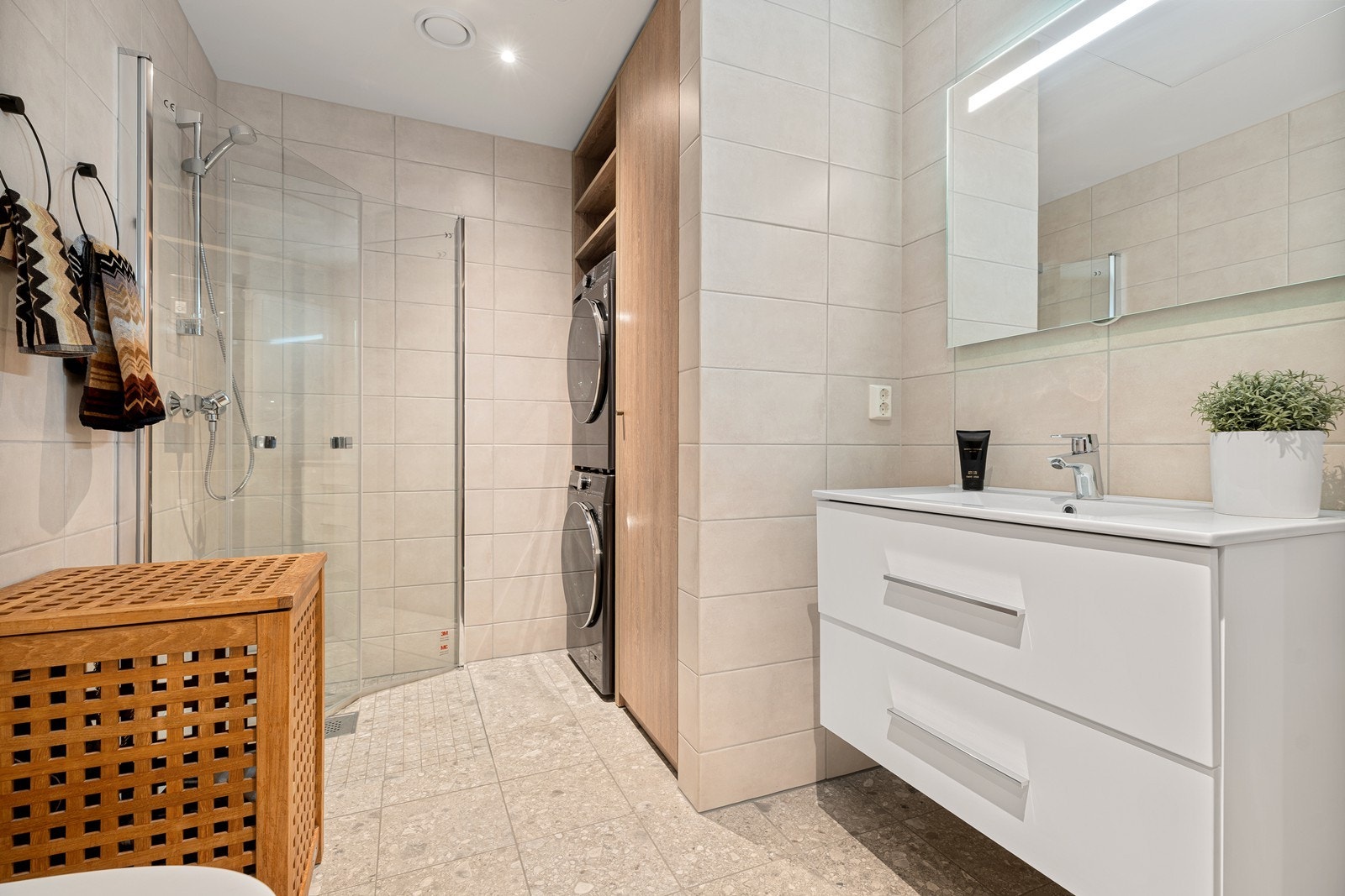 Det store badet består av vegghengt servantskap med skuffer, toalett, dusjhjørne og nisje for vask og tørk i stedbygd innredning - meget lekkert! Galleribilde