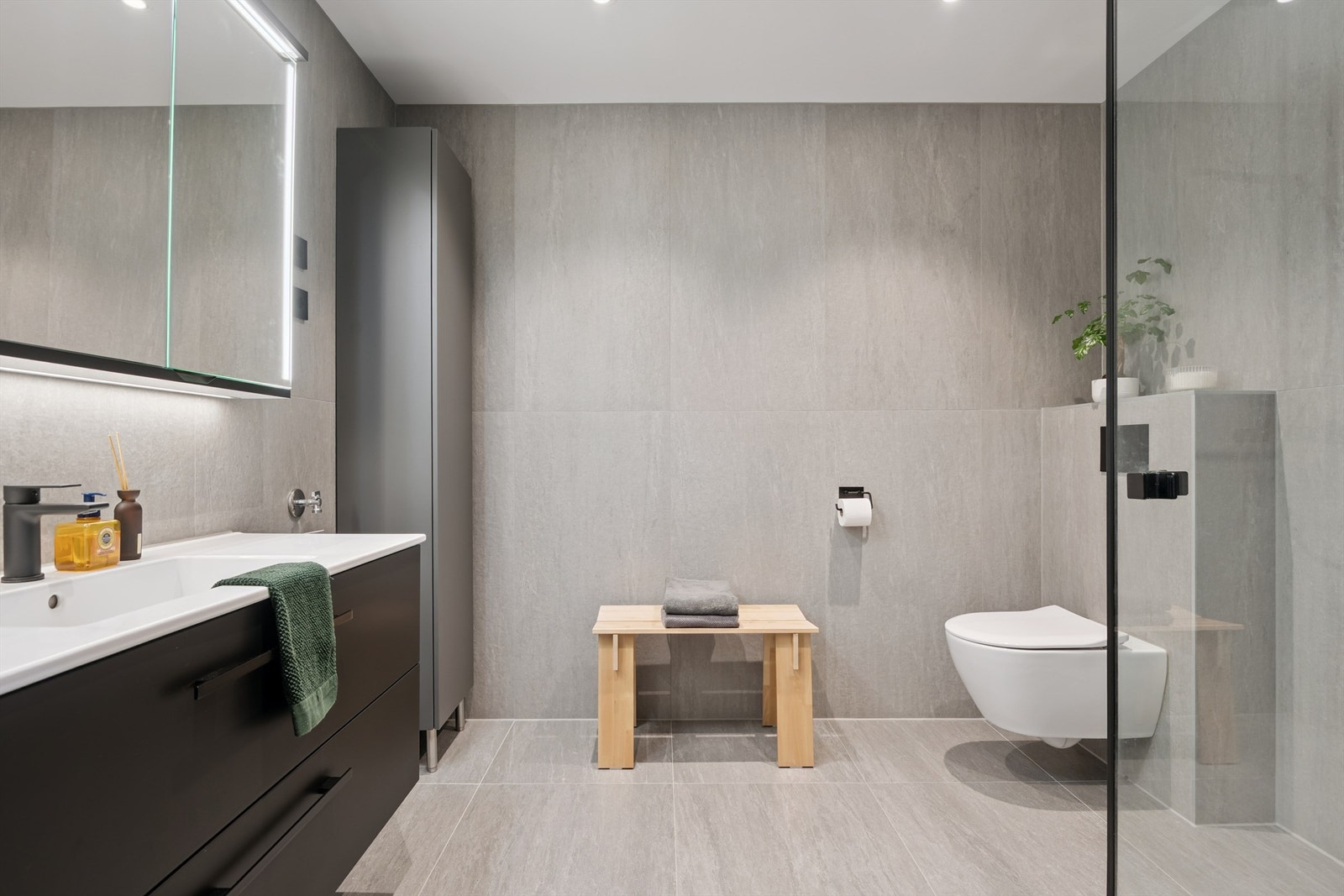 Romslig og helfliset bad med vegghengt toalett og moderne innredning. Galleribilde