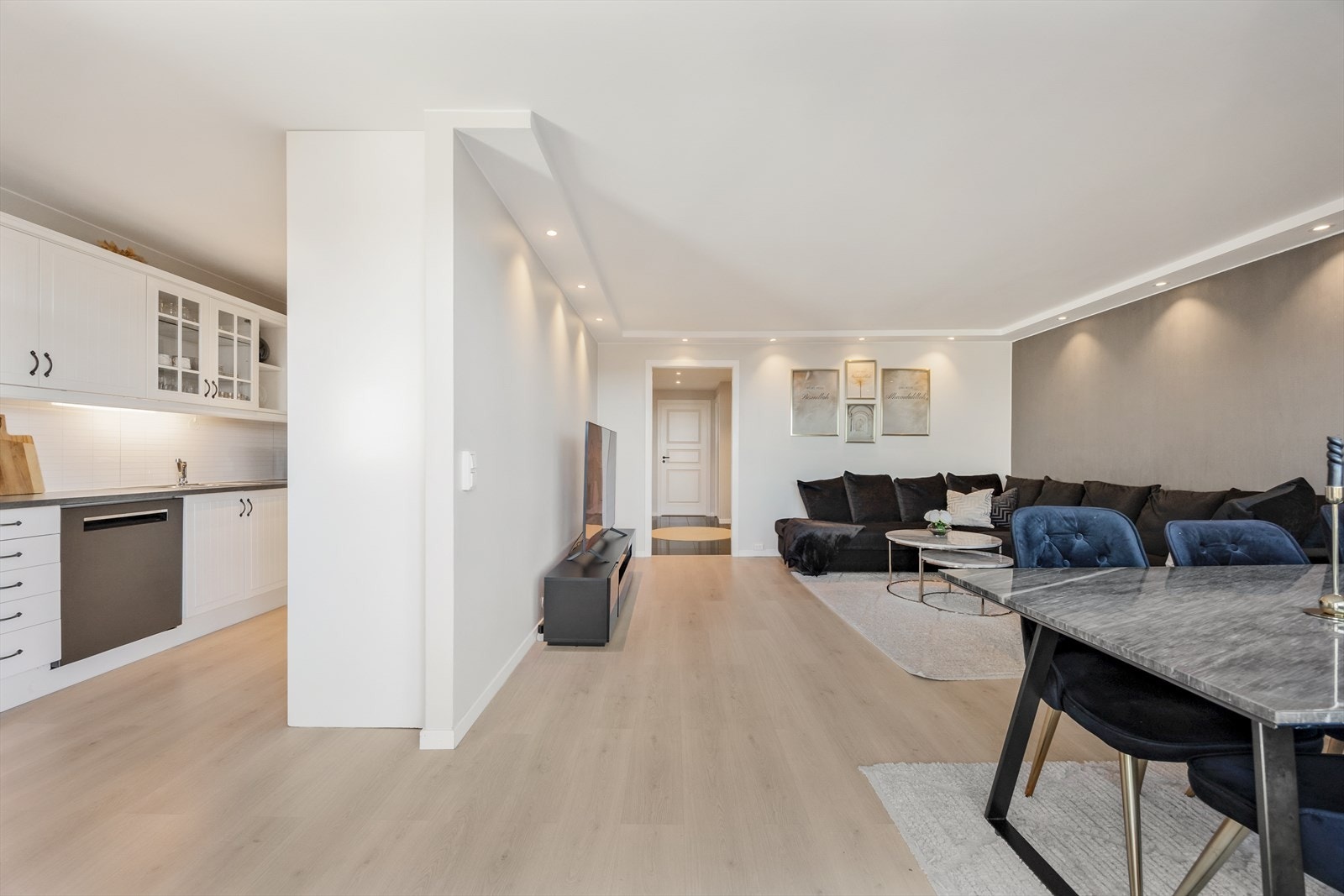 Den delvis åpne løsningen mot kjøkkenet gjør det enkelt å være sosial under matlaging. Samtidig er det et tydelig skille mellom kjøkken og stue. Galleribilde