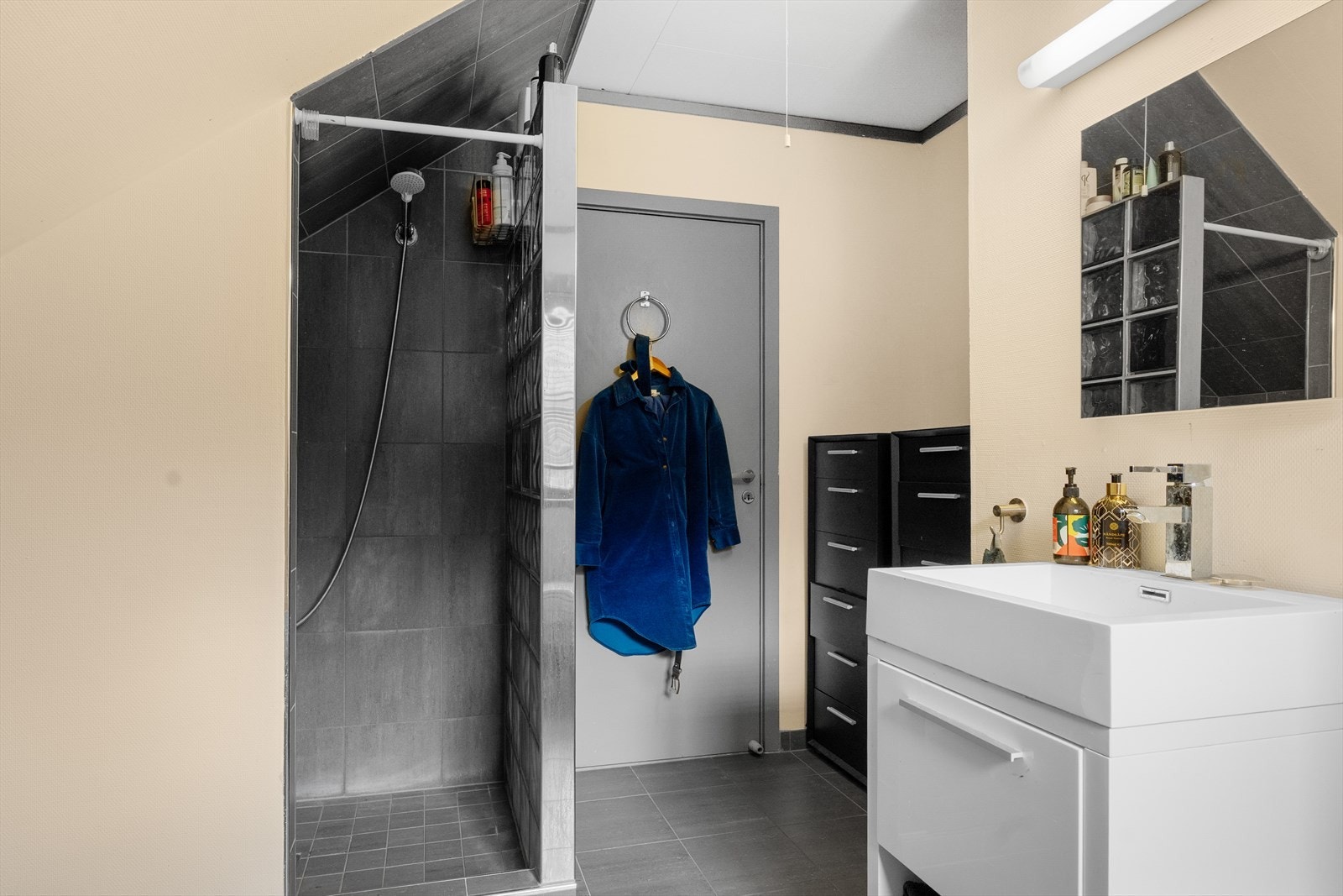 Badet har fliselagt gulv, fliser på vegg i dusj og tapetserte vegger. Galleribilde