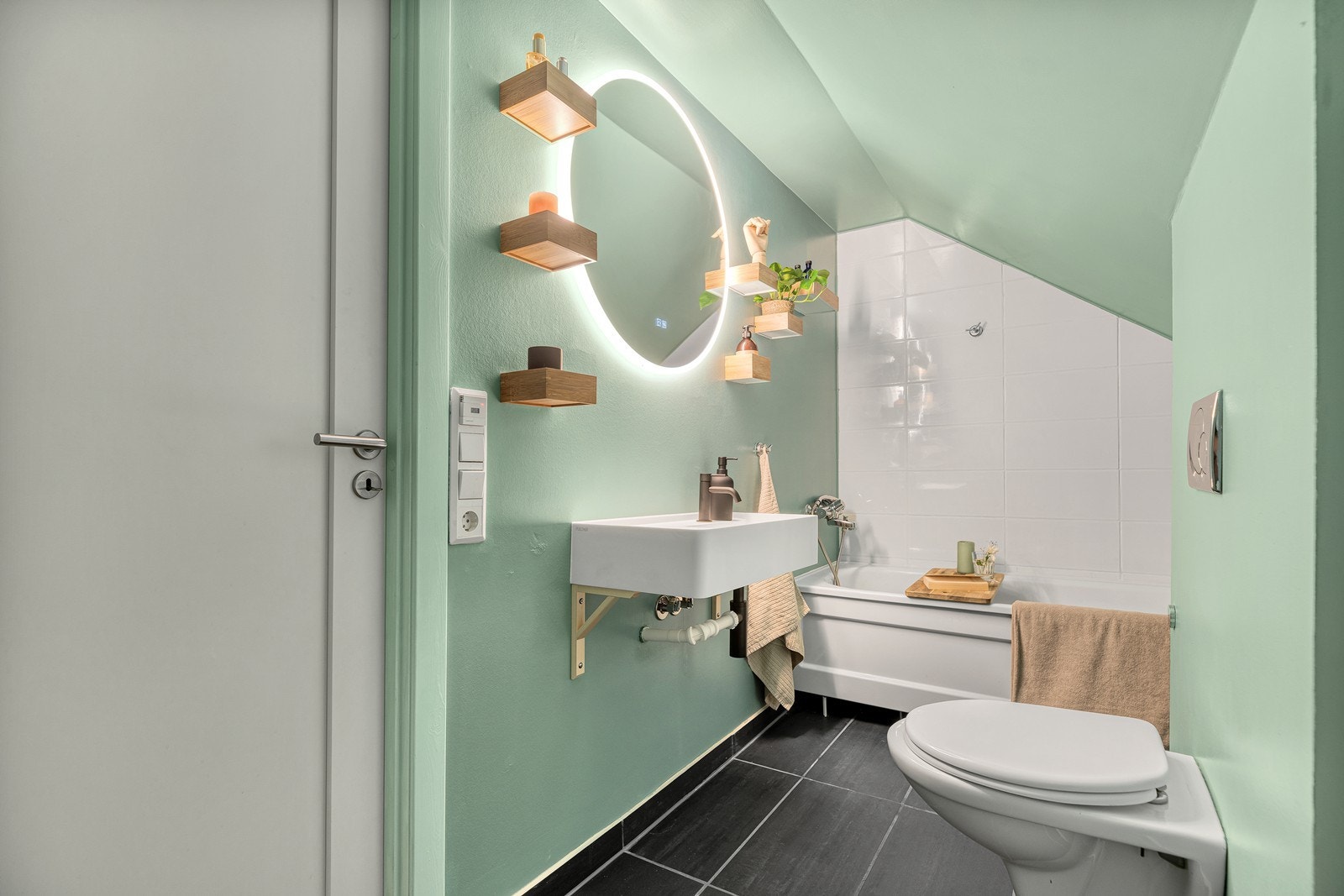 Badet er innredet med servant, vegghengt toalett, badekar og opplegg for vaskemaskin Galleribilde