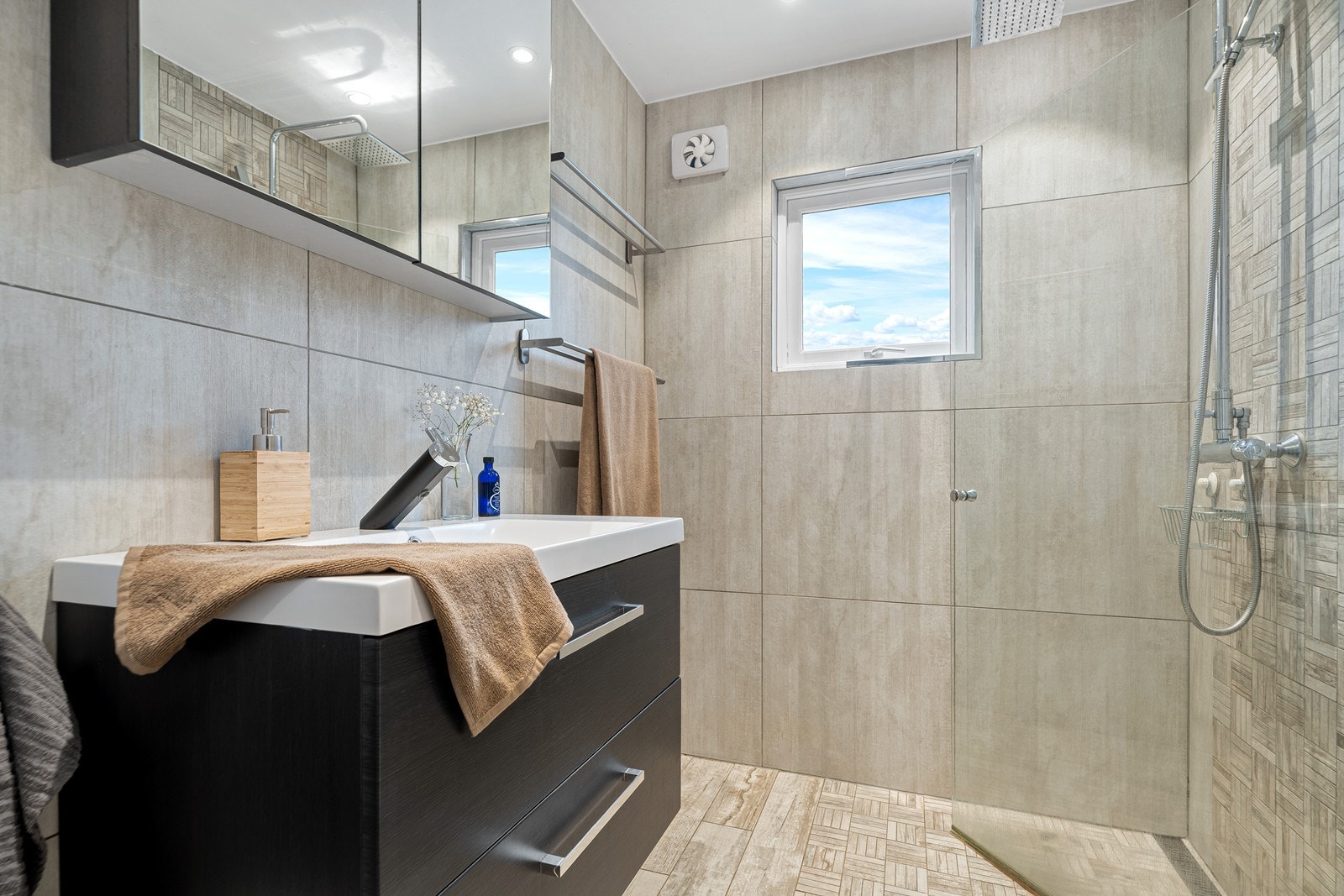 Badet er innredet med servant, vegghengt toalett og dusjhjørne med innfellbare dører Galleribilde