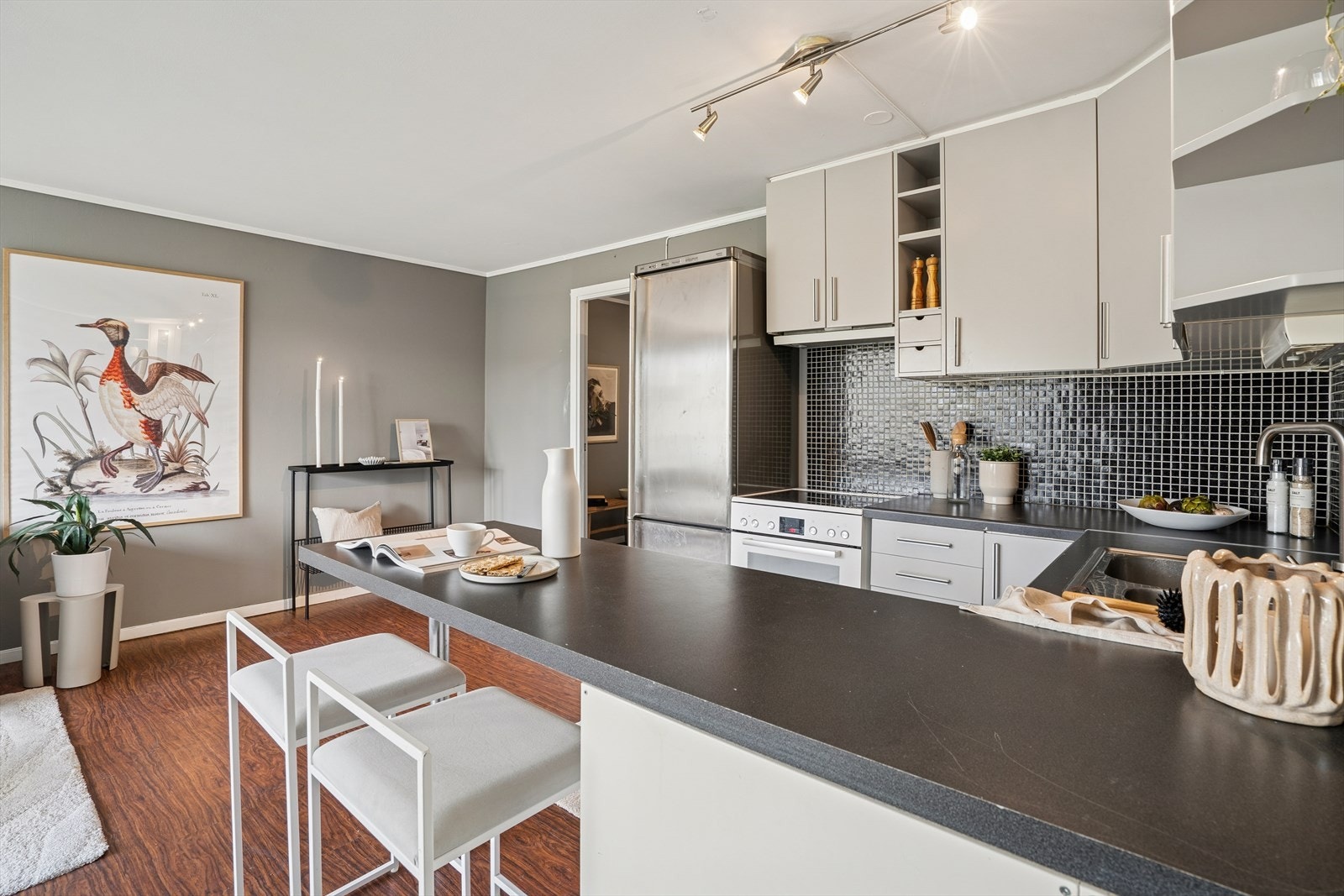 Stilfull kjøkkenløsning med grå profilerte fronter, god benkeplass og praktisk barløsning - et perfekt sted for morgenkaffen. Galleribilde