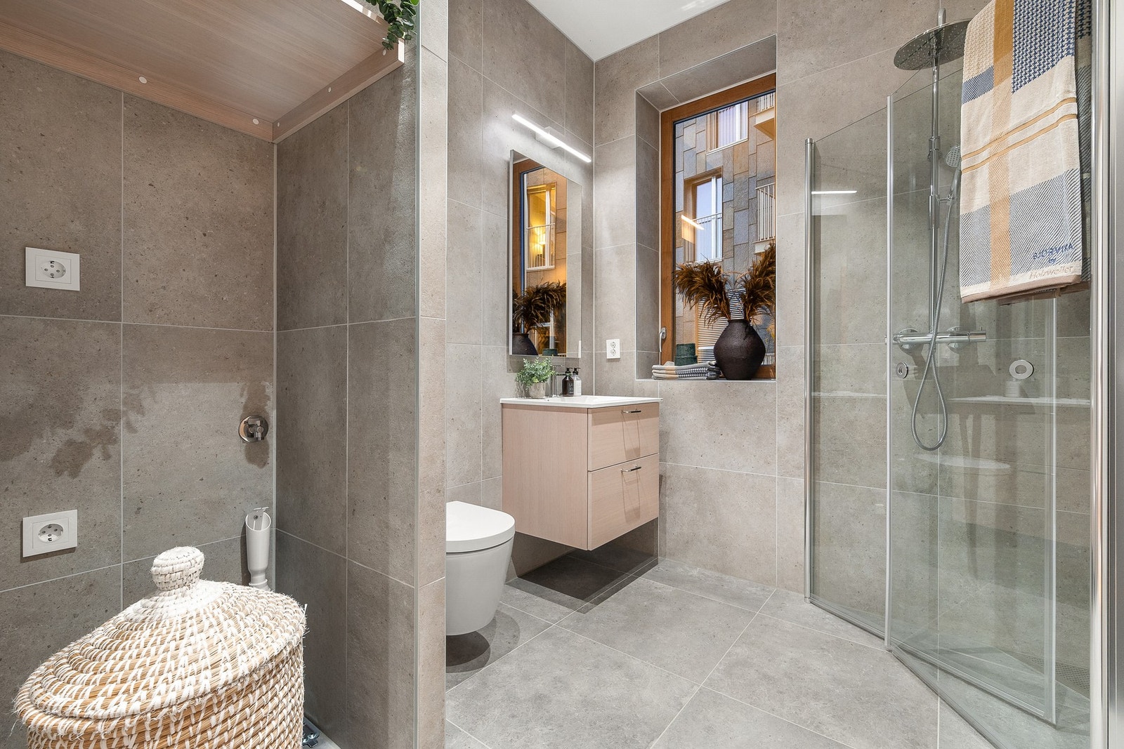 Stilrent bad med dusjhjørne, opplegg for vaskemaskin, vegghengt toalett og servantmøbel med god oppbevaring. Galleribilde