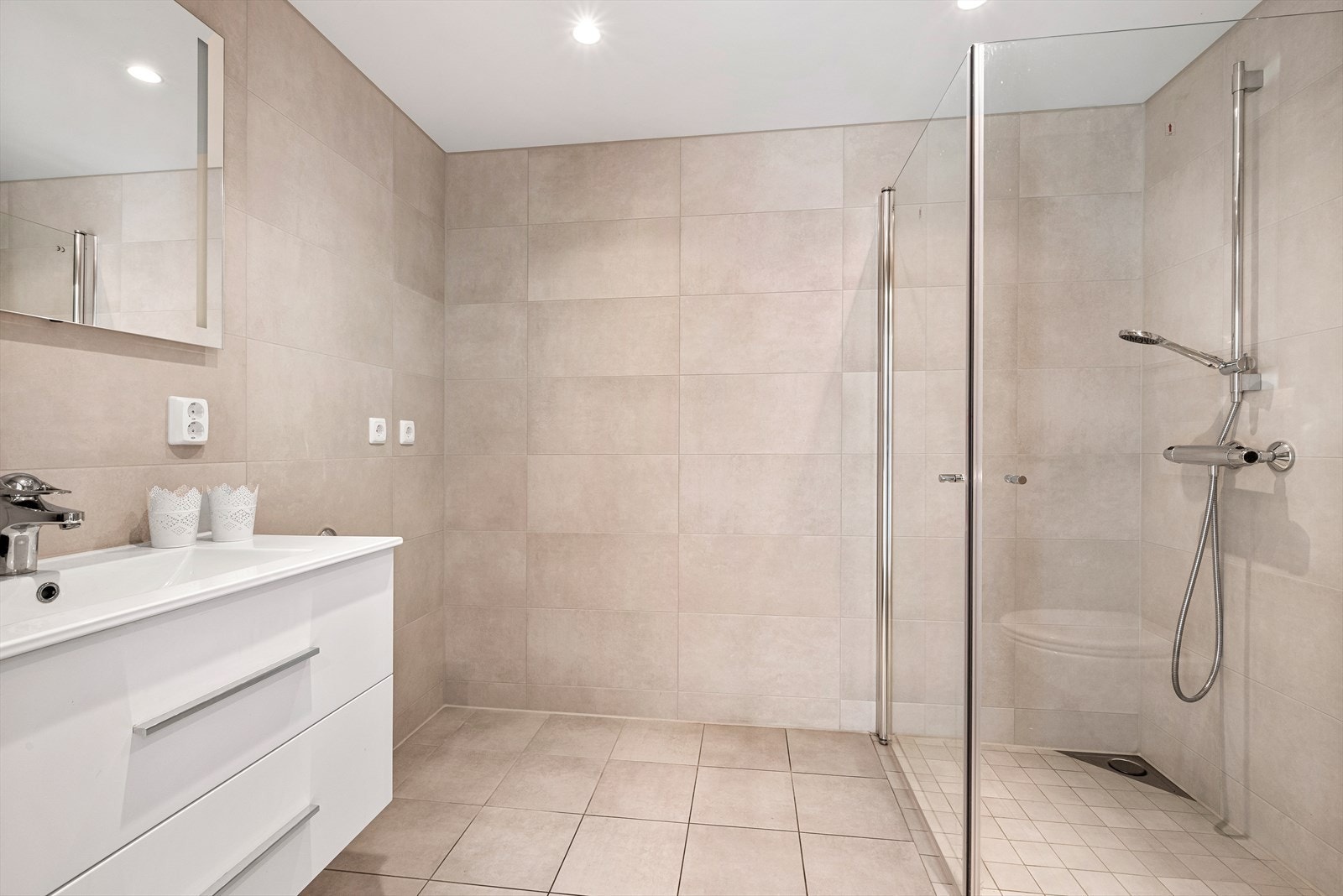 Det lekre badet på 5 kvm er utstyrt med fliser på gulv og vegger, og byr på en flott, lys baderomsinnredning. Galleribilde