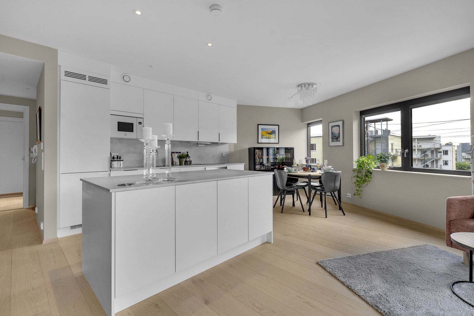 Lys og romslig stue med et moderne og stilrent fargevalg. Det er god plass til både salong og spisestuemøblement, pent delt inn i naturlige soner. Den åpne og luftige planløsningen mellom stue og kjøkken understreker boligens moderne preg. Galleribilde