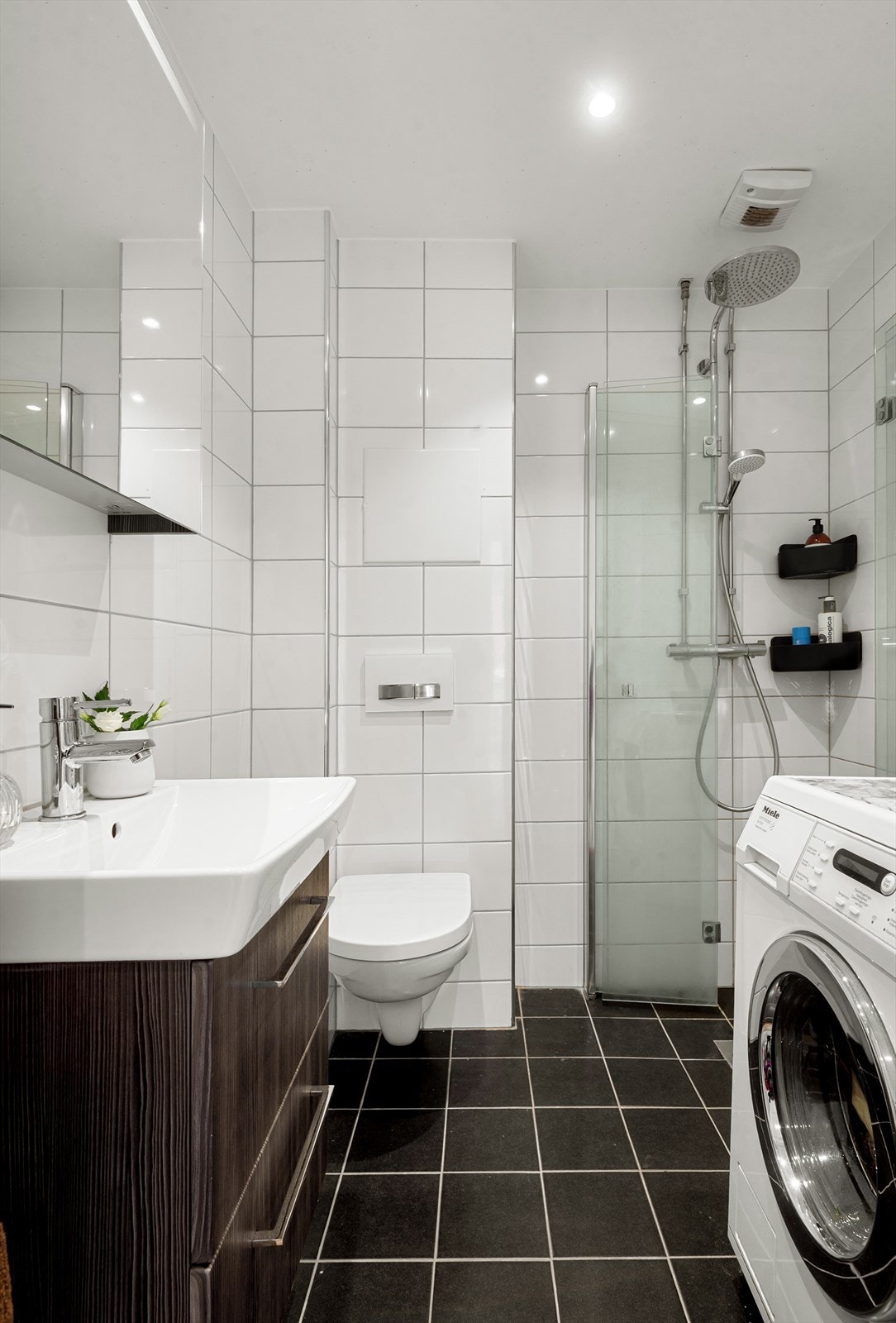 Badet har varme i gulv, doble innfellbare dusjdører, opplegg for vaskemaskin og speilskap Galleribilde