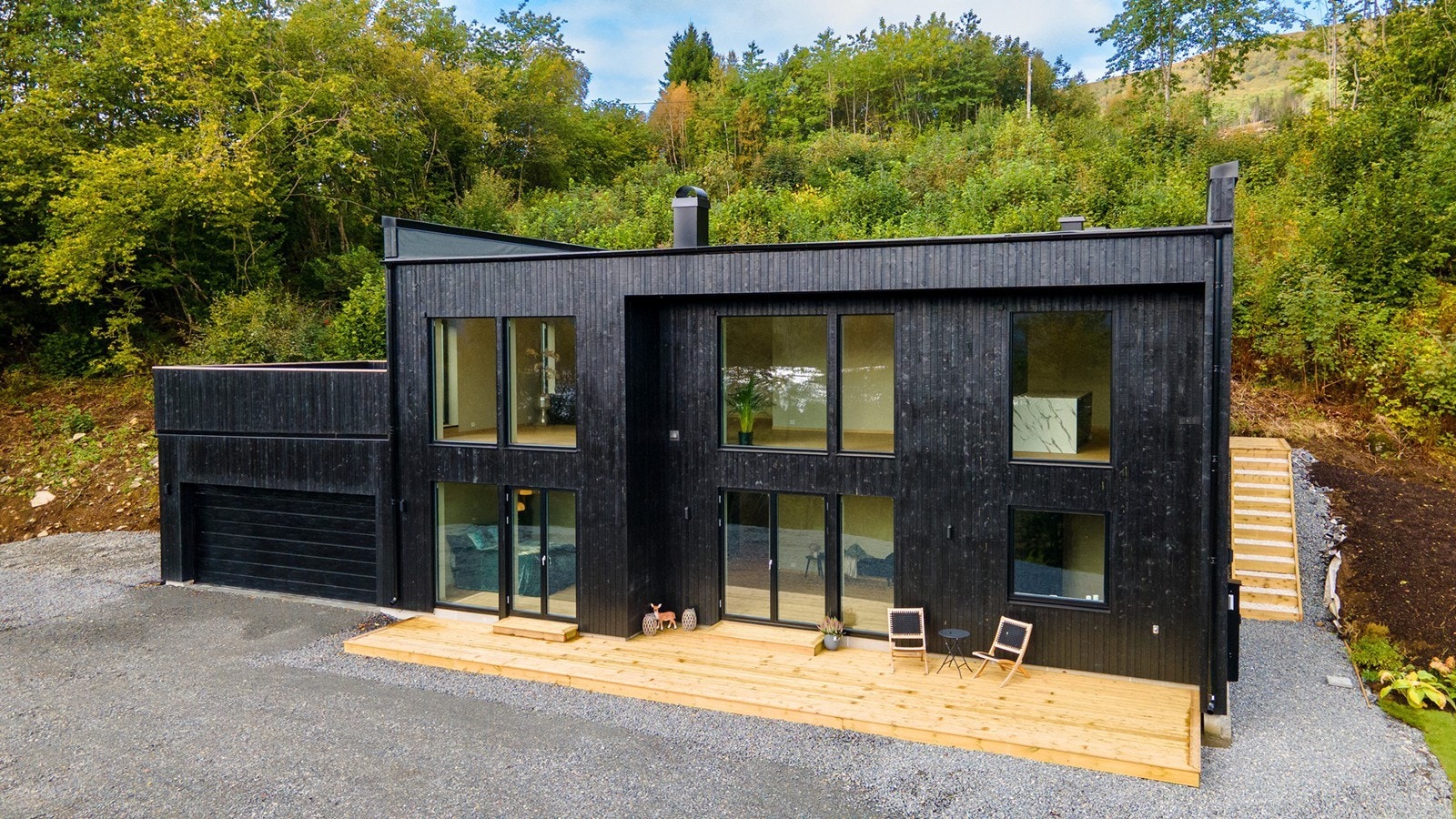 Stilren fasade med store vindusflater og terrasseplatting på 33m² foran huset Galleribilde