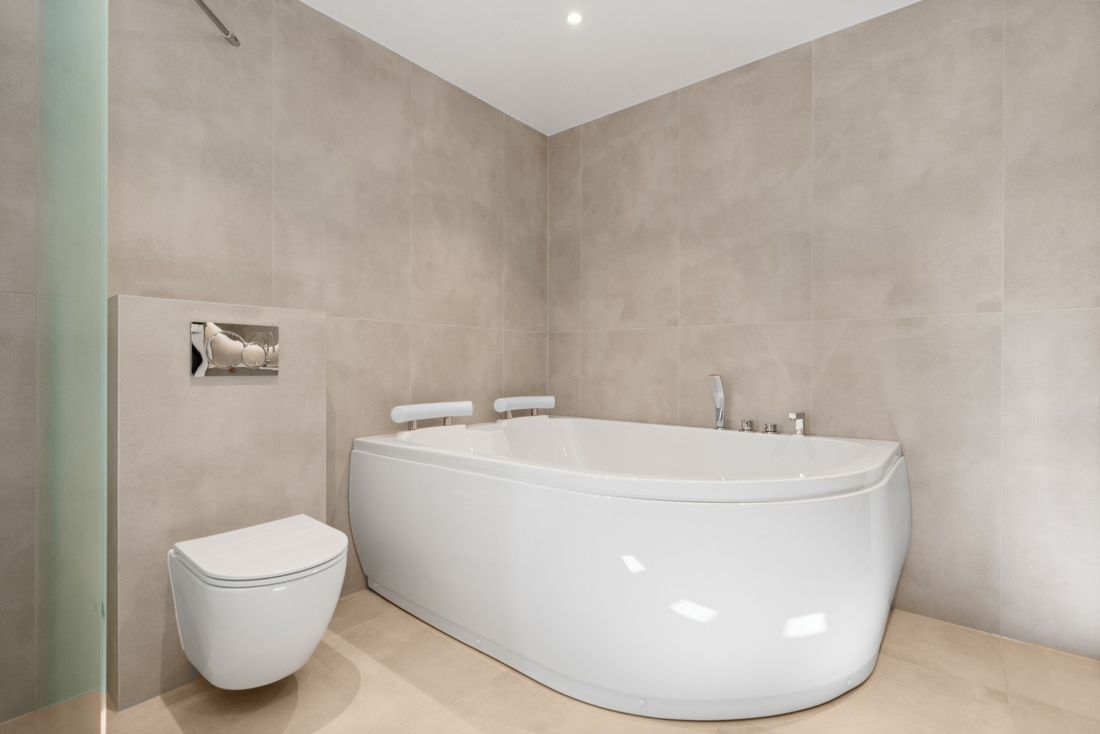 Pent flislagt bad/vaskerom med varmekabler fra 2025. Rommet har innredning med nedfelt servant, veggfestet toalett, badekar og opplegg for vaskemaskin. Galleribilde