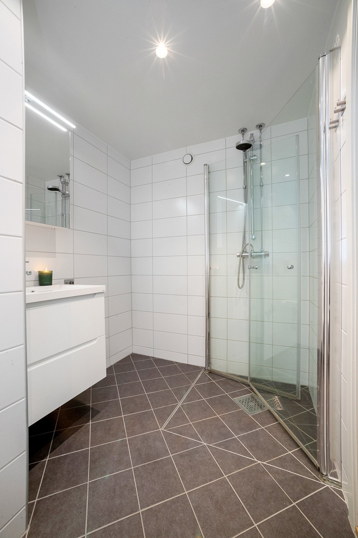 Innredningen består av vegghengt klosett, servant på innredning og dusjvegger med svingbare dører. Galleribilde