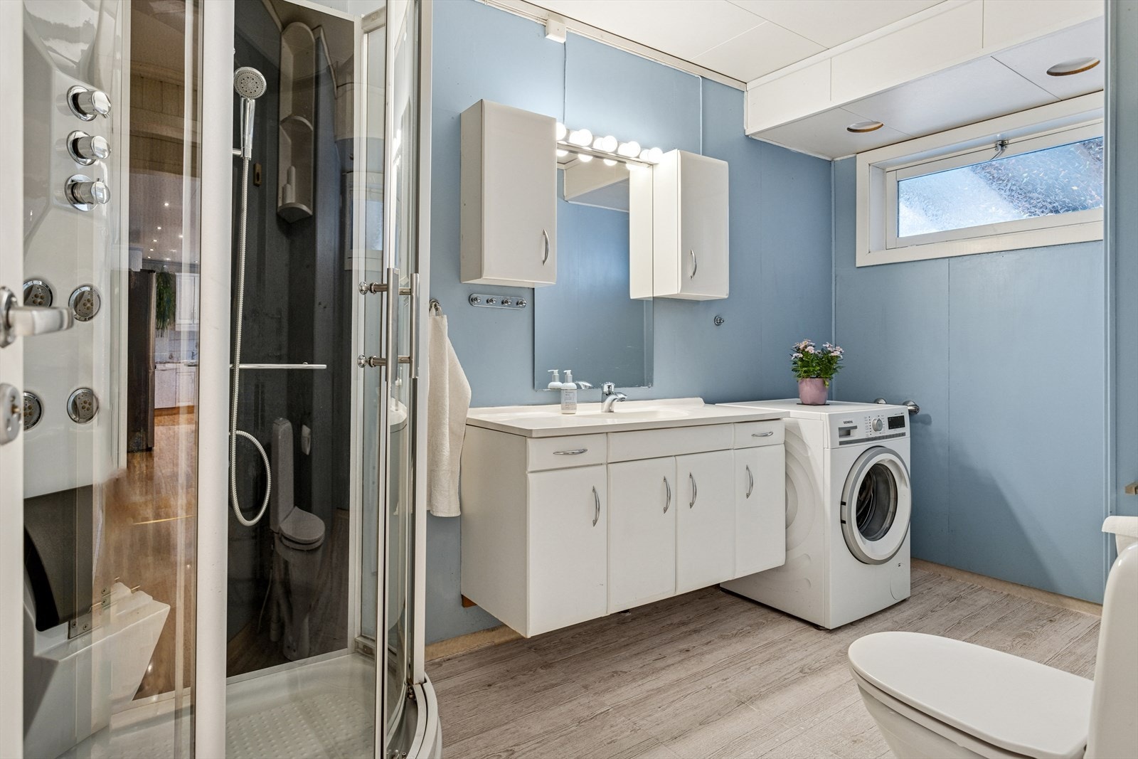 Baderommet er innredet med dusjkabinett, toalett og veggseksjon med servant. I tillegg har man opplegg for vaskemaskin. Galleribilde
