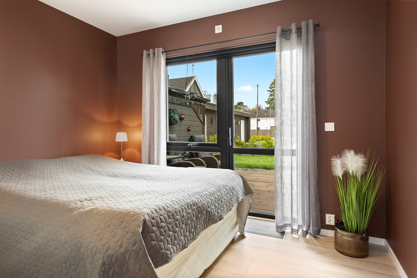 Et av soverommene i i 1. etasje er malt i rustrød tone og har god plass til seng. Rommet har utgang til koselig terrasse og uteplass. Galleribilde