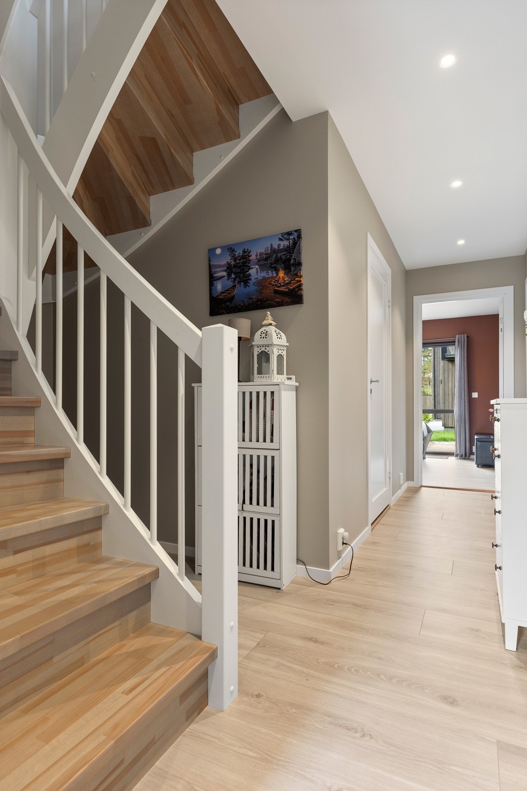 Fra 1. etasje leder en trapp med trefargede trinn og hvimalt rekkverk opp i 2. etasje. Galleribilde