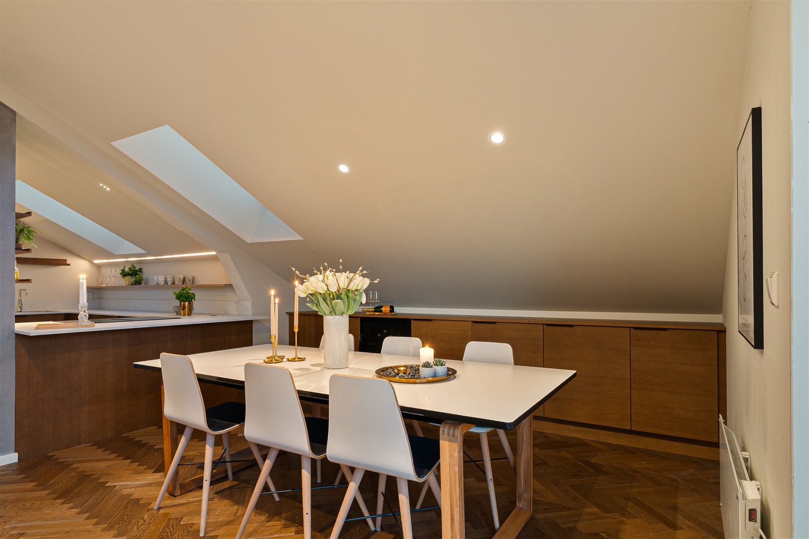 Romfølelsen er åpen, lun og god, og forsterkes av varme fargenyanser i gulv og skapfronter. Galleribilde