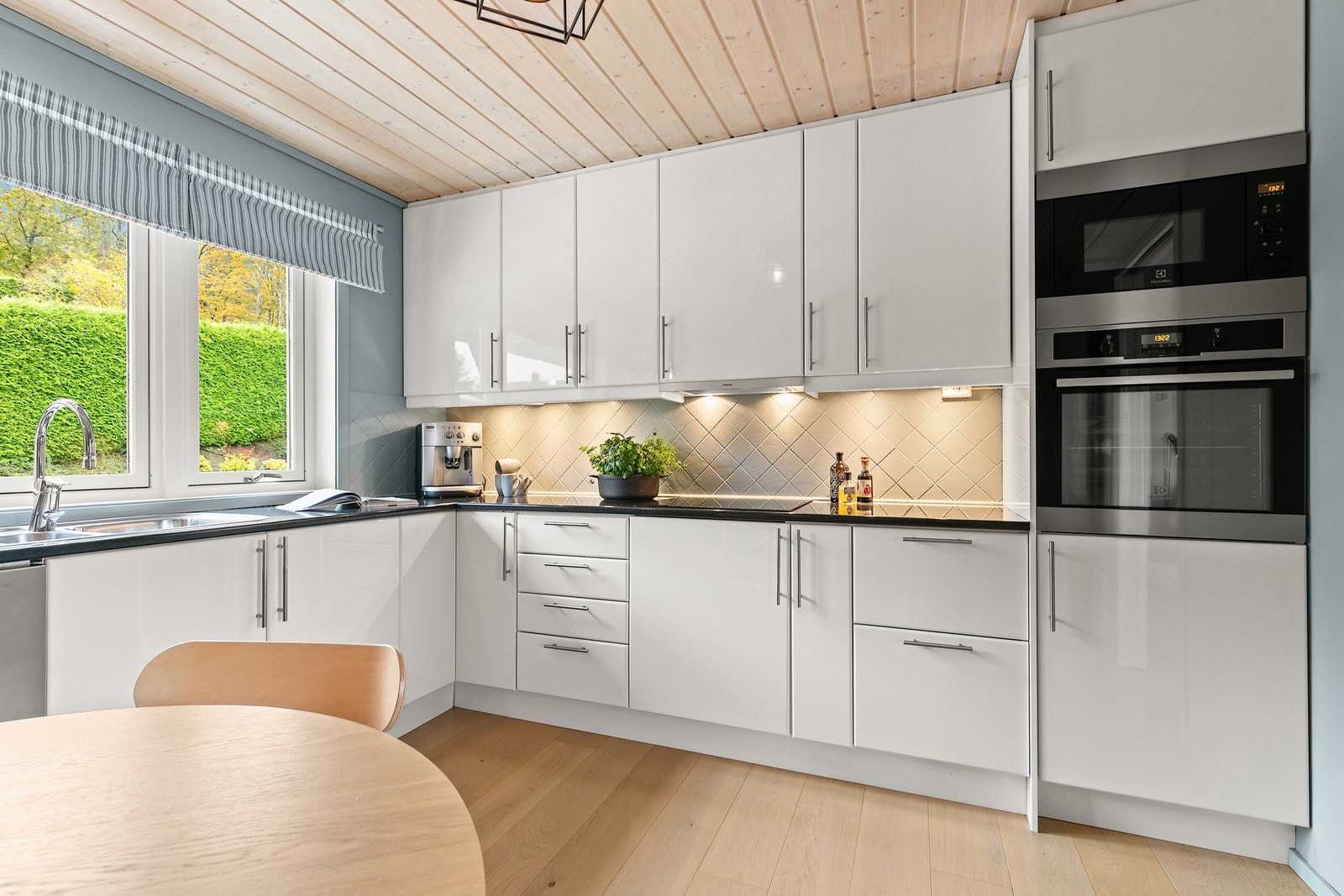 Integrerte hvitevarer, heltre benkeplate og stilfullt flisfelt over benk. Galleribilde