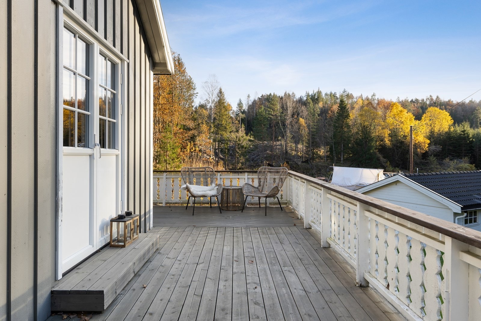 Utgang fra stue/spisestue til en terrasse som strekker seg rundt husveggen. Galleribilde