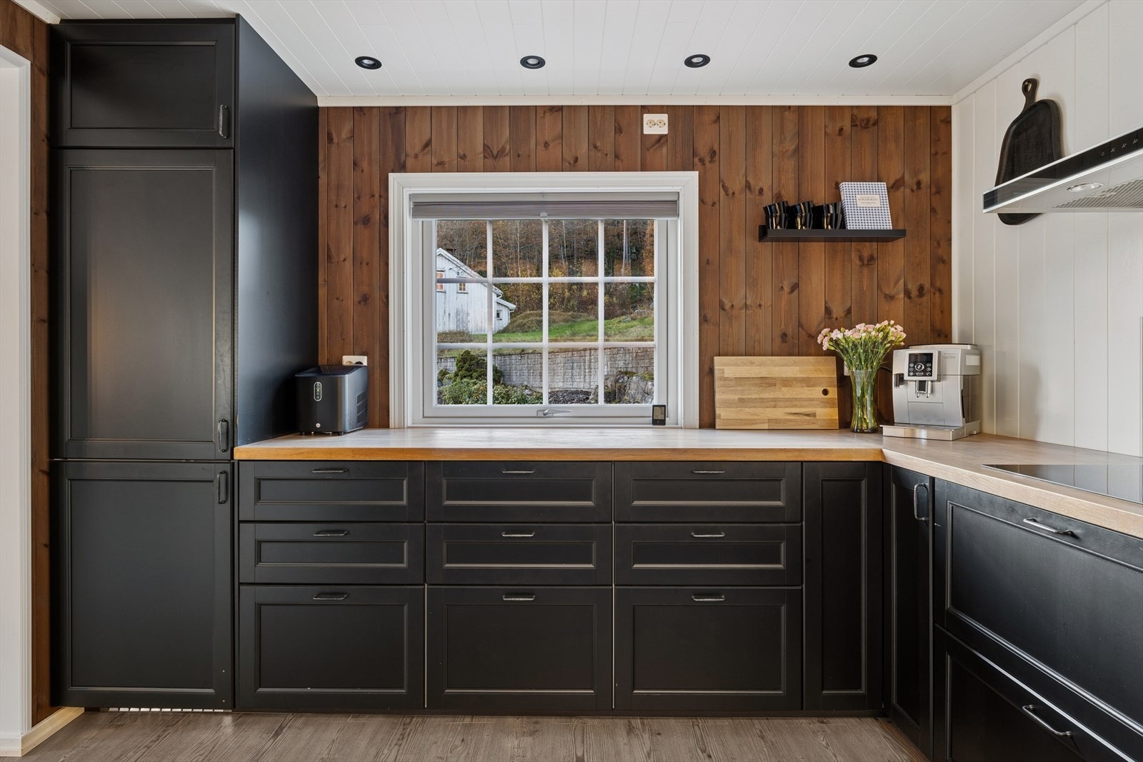 Kjøkkenets innredning har profilerte fronter, heltre benkeplate og belysning under overskap. Galleribilde