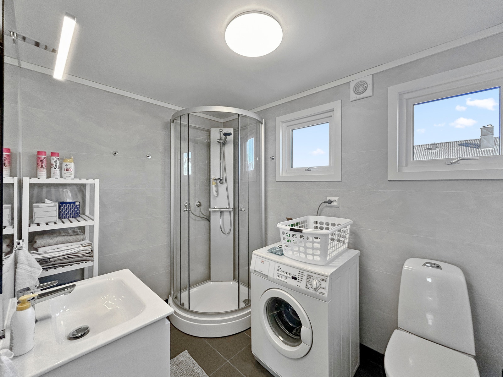 Baderom med dusjkabinett og opplegg til vaskemaskin. Galleribilde