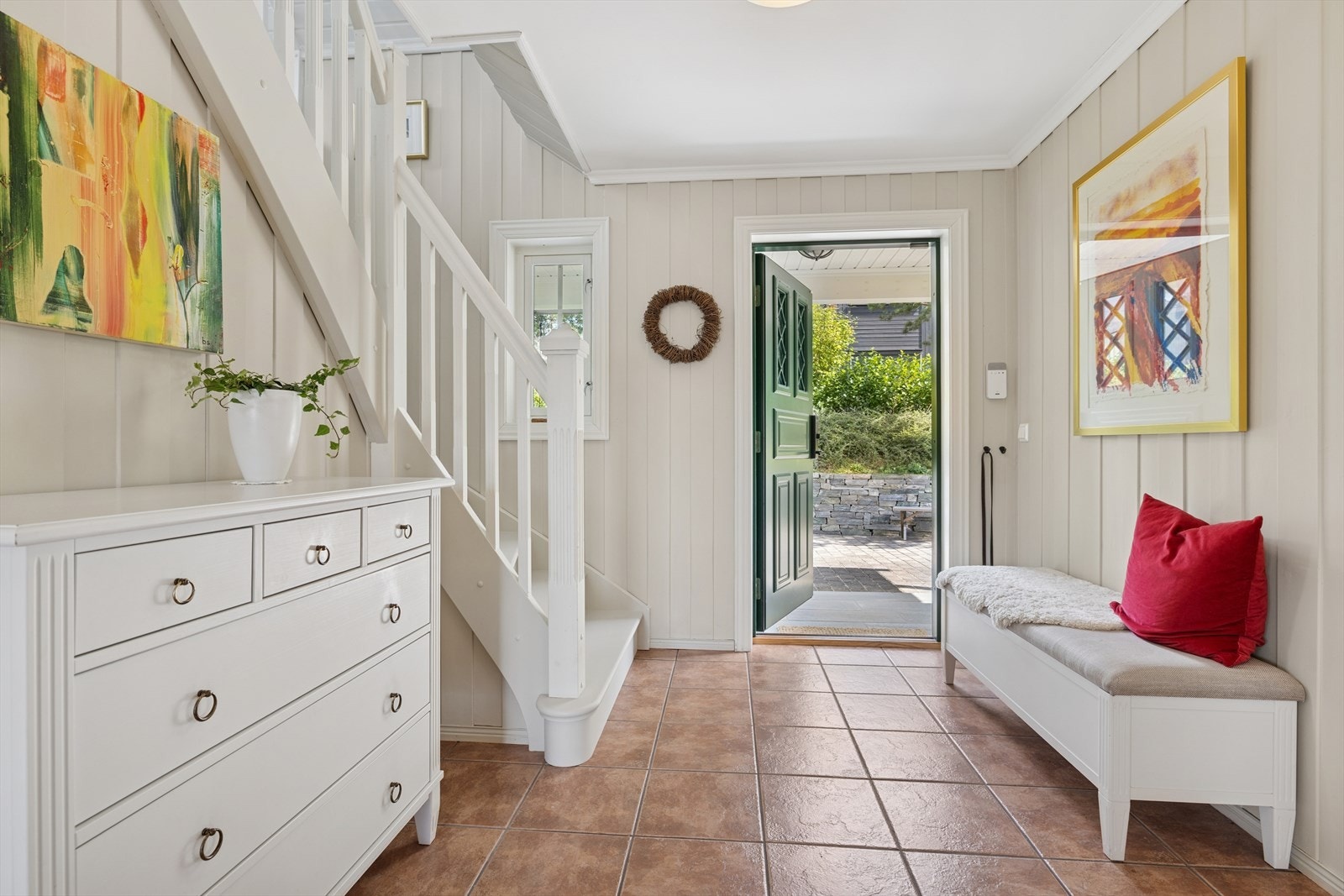 En lys og åpen hall, utstyrt med garderobe og trapp som binder sammen både andre etasje og underetasjen Galleribilde