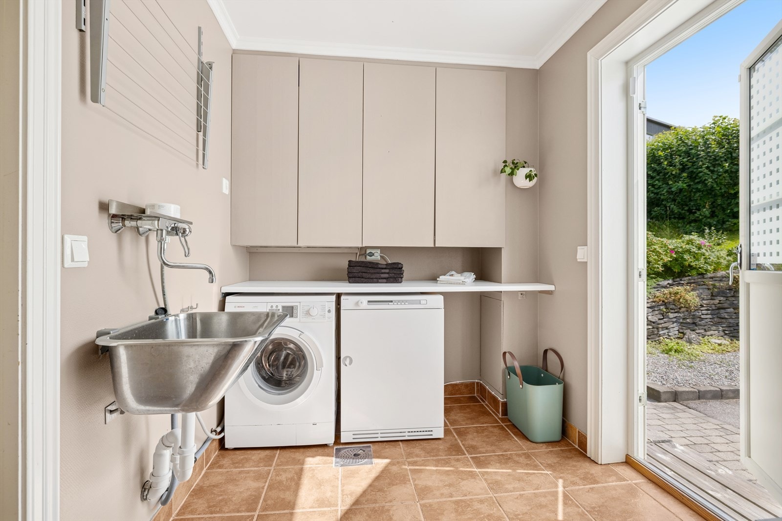 Separat vaskerom har egen utgang, utslagsvask, dusjkabinett, opplegg for vaskemaskin og rikelig skapplass - praktisk og funksjonelt i hverdagen. Galleribilde