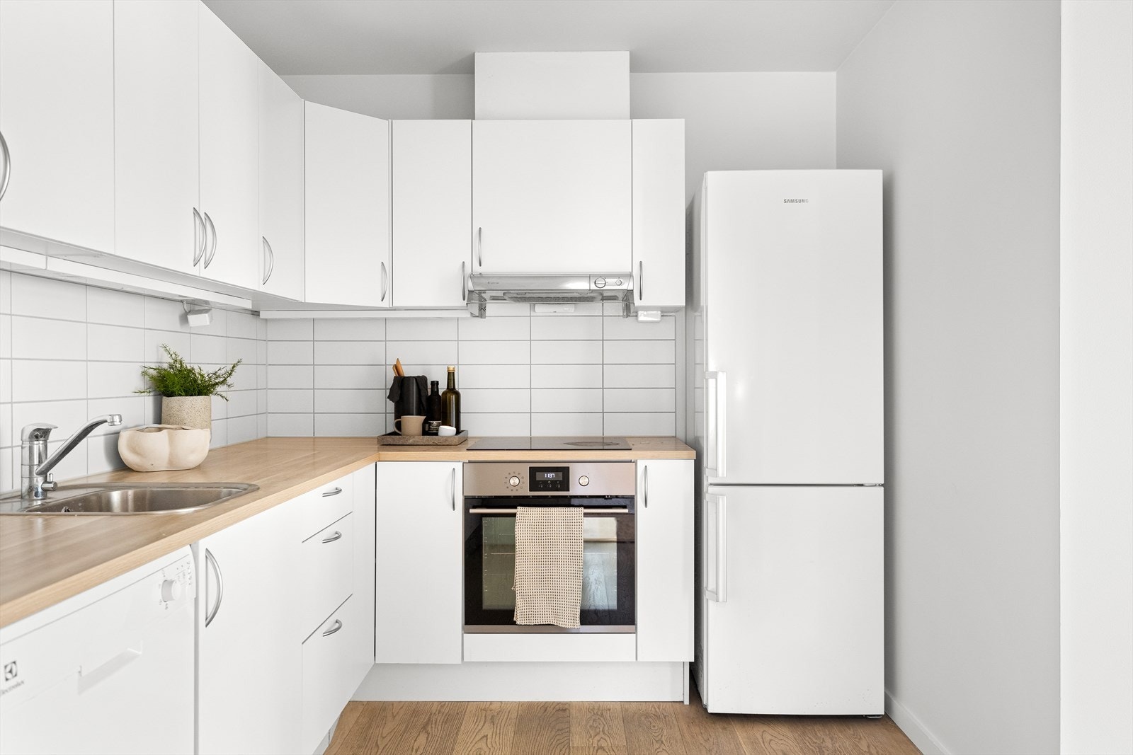 Hvit foliert kjøkkeninnredning med glatte fronter og frittstående kjøleskap med fryser Galleribilde