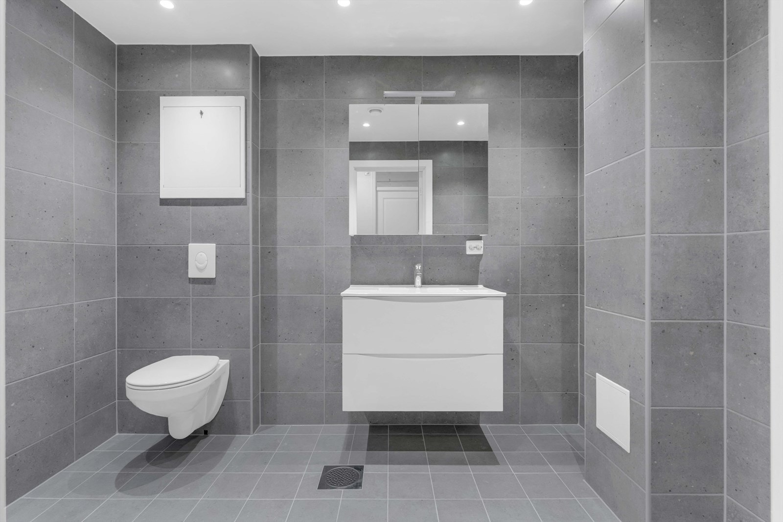 Leiligheten inneholder et bad/wc og et vaskerom, og begge er totalrenovert i 2025. Begge rommene har downlights i himlingen, mekanisk avtrekk, grå fliser på veggene og matchende fliser på gulv med gulvvarme. Galleribilde