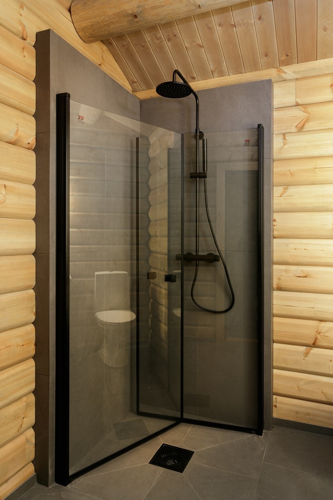 Dusjhjørne på bad med foldbare glassvegger og vegghengt dusjarmatur med hånddusj og takdusj. Galleribilde