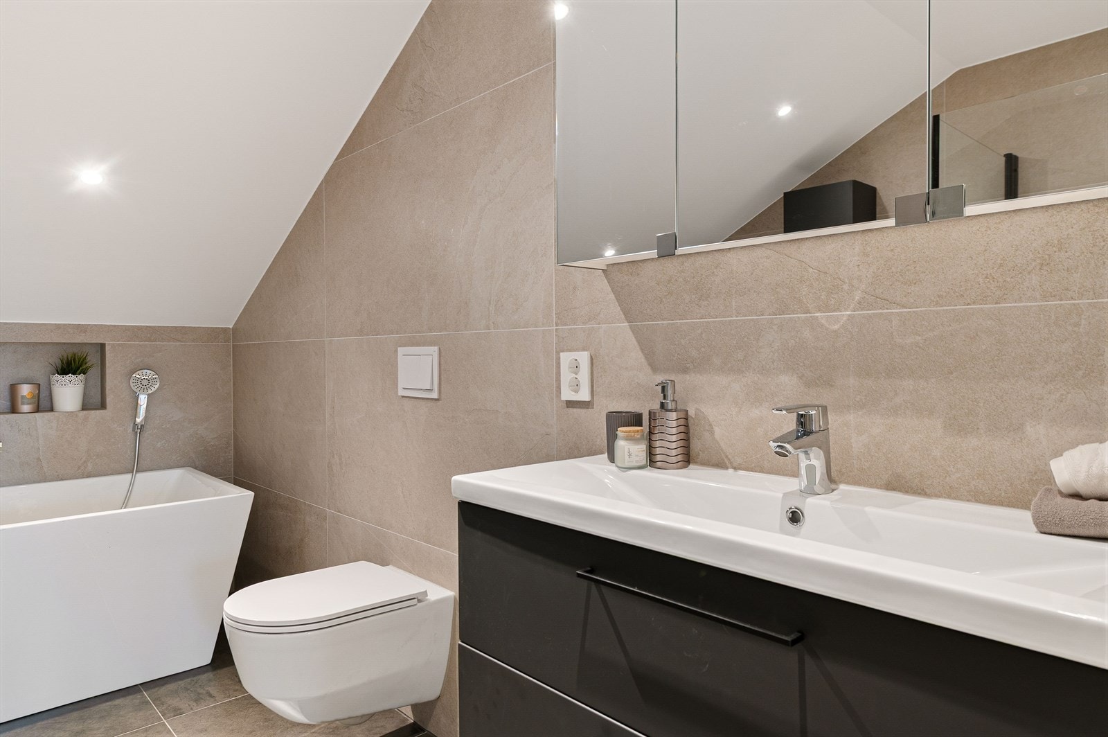 Rommet har innredning med nedfelt servant, veggmontert toalett, badekar og dusjvegger/hjørne. Galleribilde