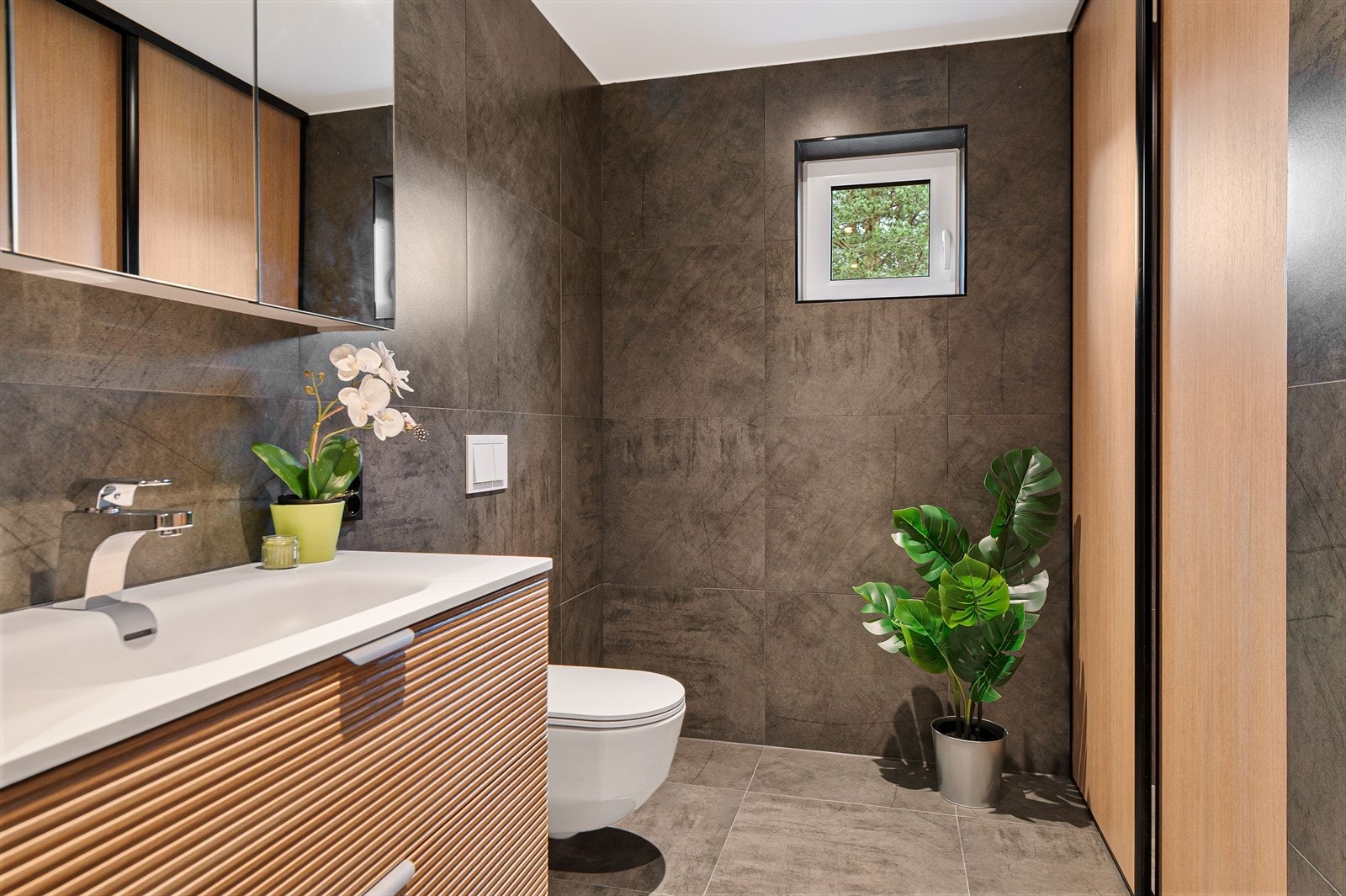 Rommet har innredning med nedfelt servant, veggmontert toalett, dusjvegger/hjørne og opplegg for vaskemaskin. Galleribilde