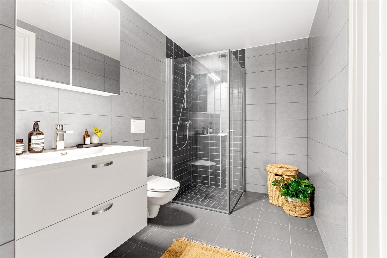 Pent og flislagt bad med stor servant, vegghengt toalett og dusj. Galleribilde