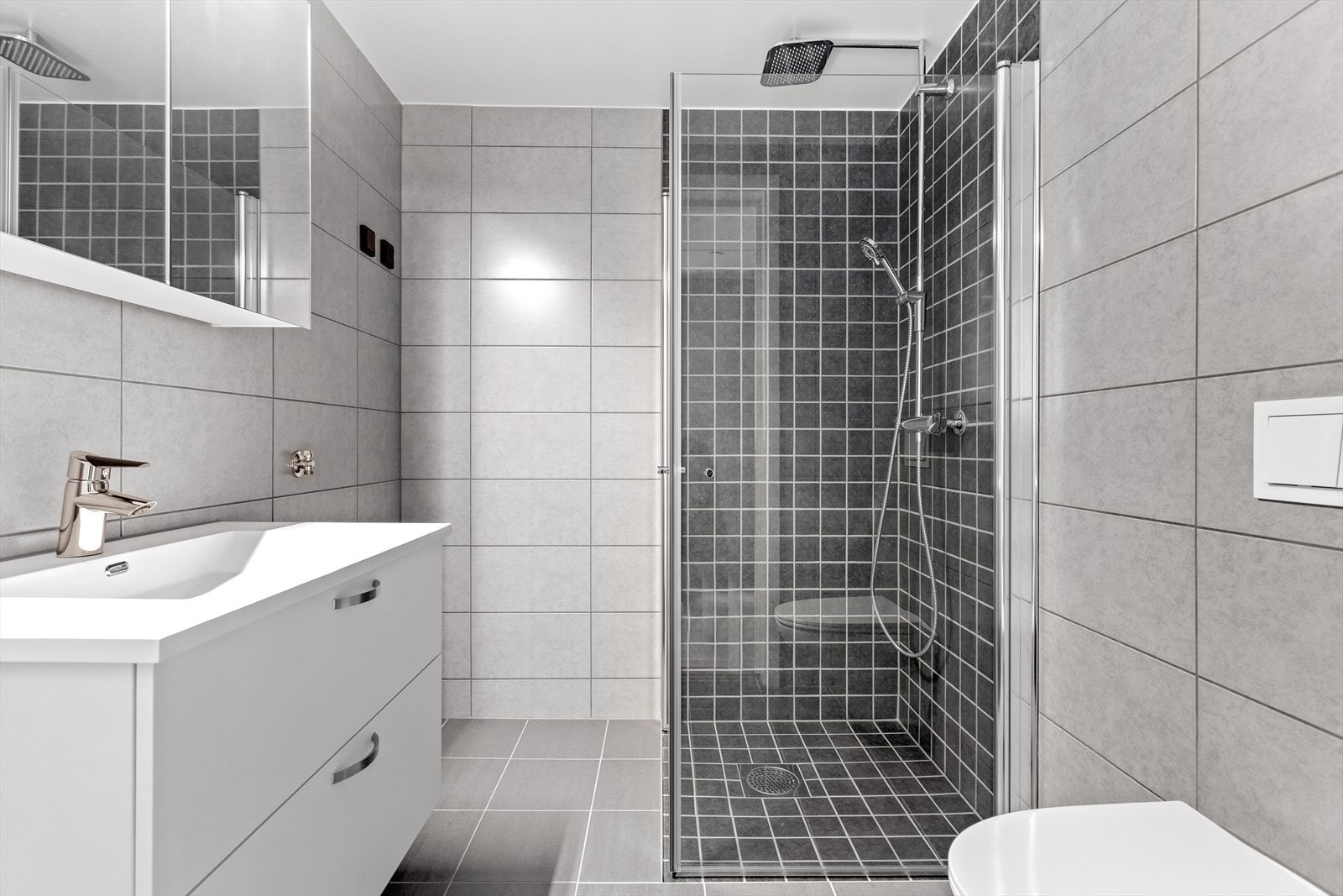 Delikat bad med servant, dusj, vegghengt toalett og opplegg for vaskemaskin og tørketrommel. Galleribilde