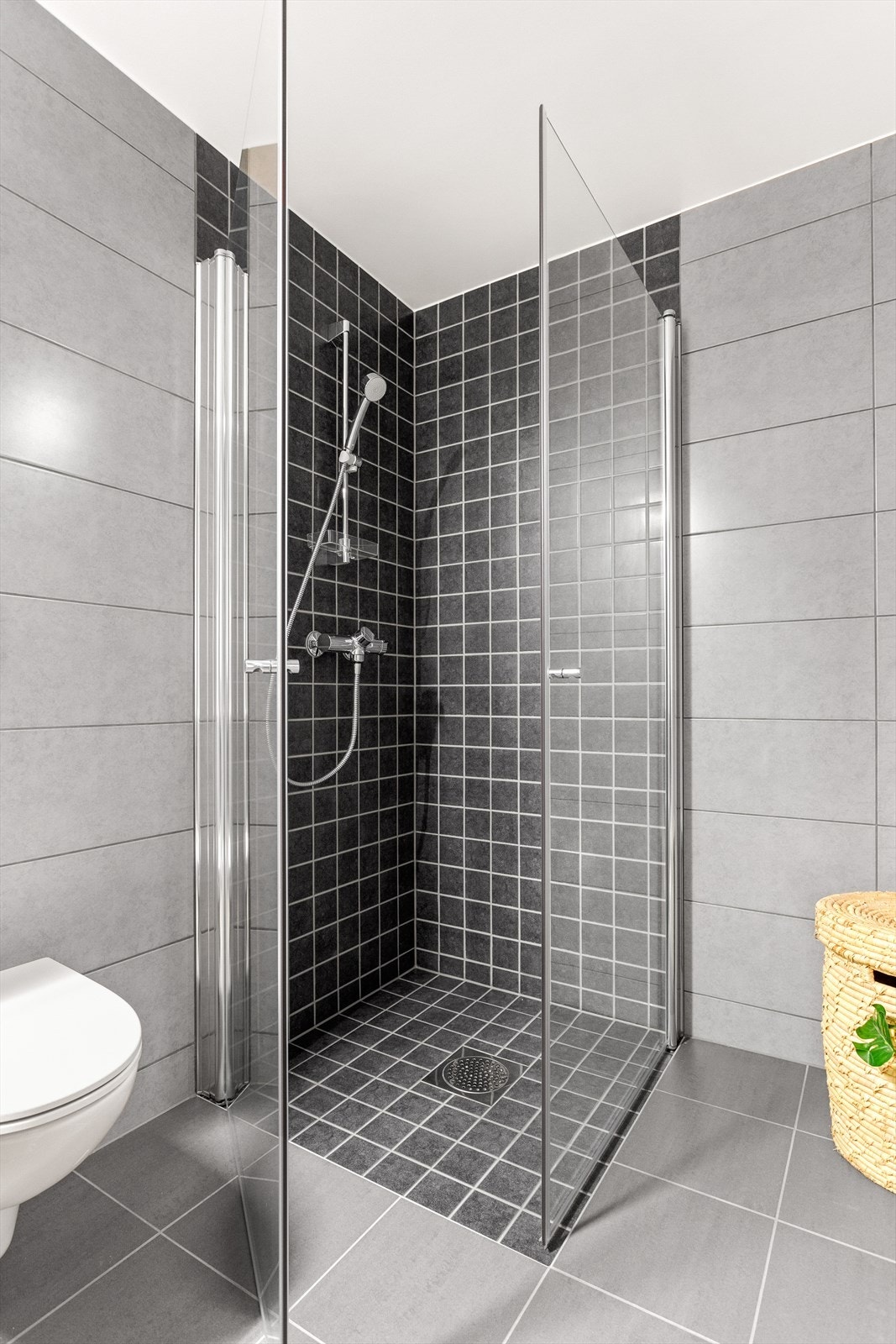 Dusj med innfellbare plassbesparende glassdører. Det er også mindre og delikate fliser i dusjssonen. Galleribilde