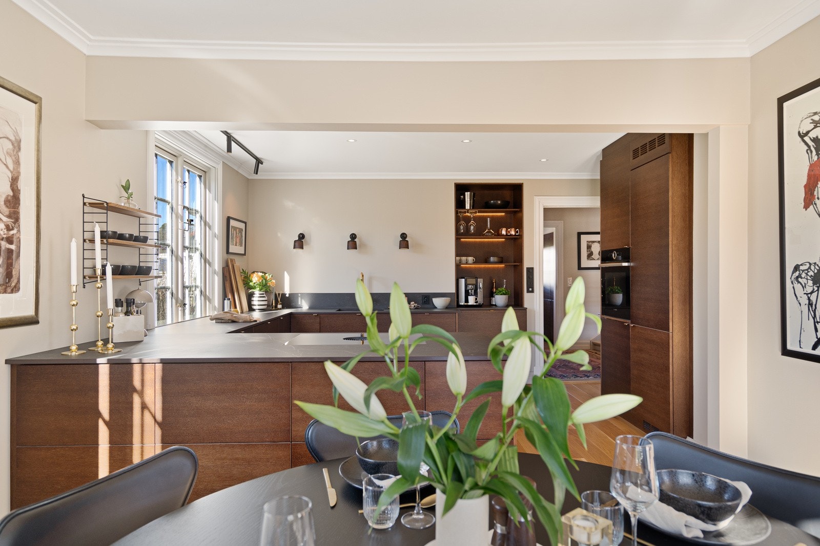 For et luftigere uttrykk er overskap droppet til fordel for åpne flater og en stor hylle med innfelt lys, men det er likevel rikelig med skap- og benkeplass på kjøkkenet. Galleribilde