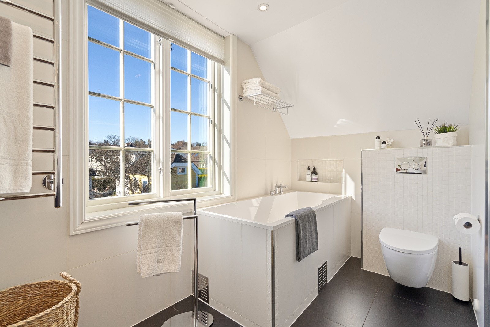 Downlights, varmekabler og vegghengt toalett er installert, og badet er innredet med store fliser i sort og lysebeige. Galleribilde