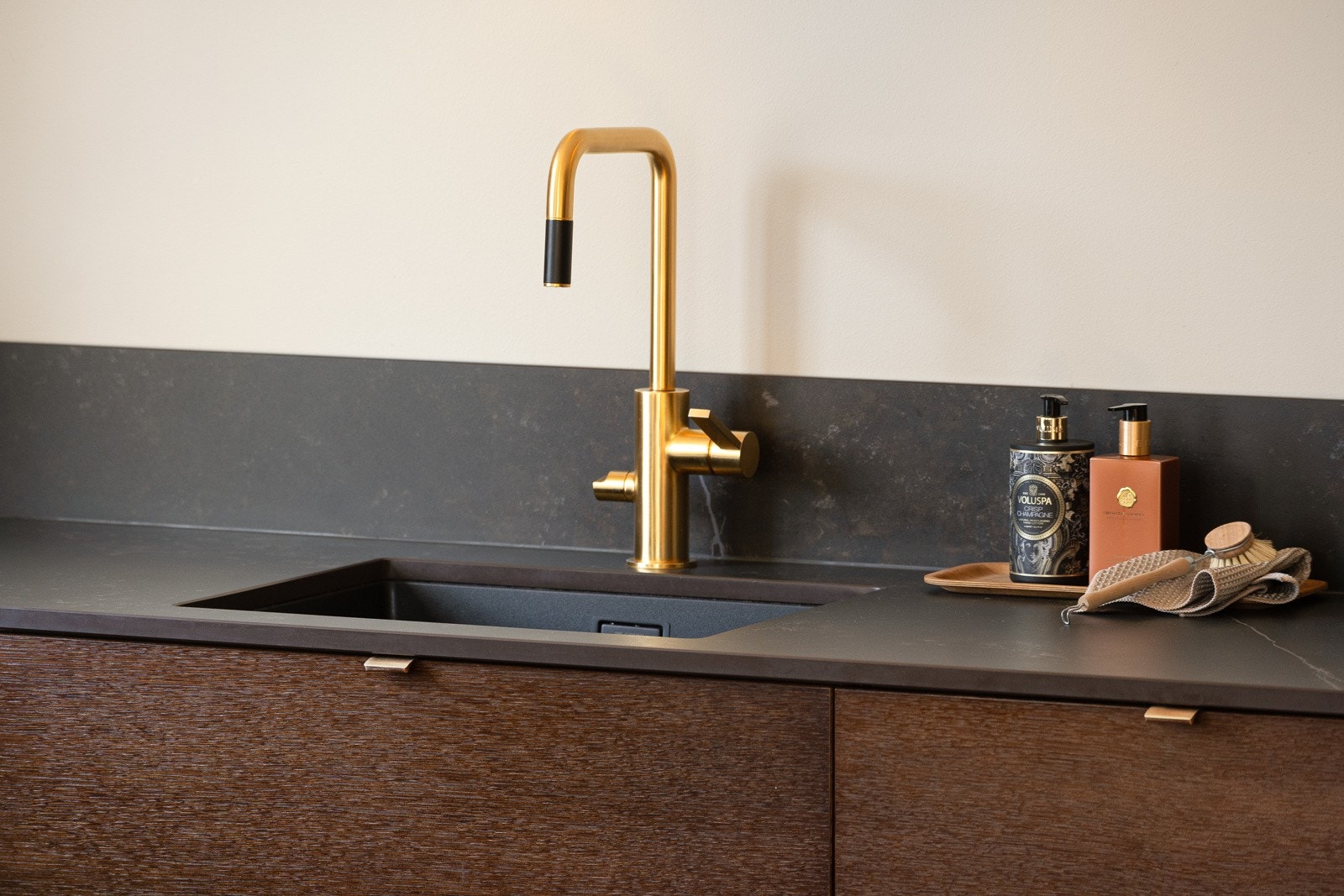 Frontene er glatte og jordfargede, og kjøkkenet har Dekton benkeplate og nedfelt oppvaskkum med gullfarget armatur. Galleribilde