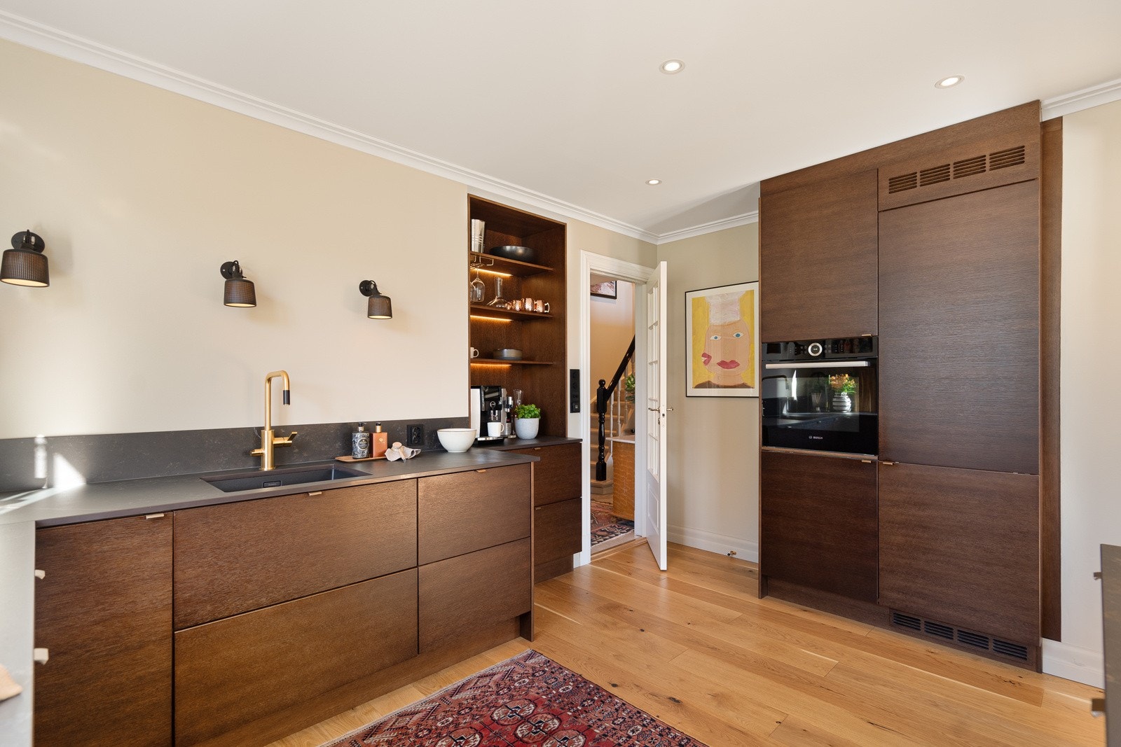 Integrerte hvitevarer; platetopp, kjøleskap, fryser, oppvaskmaskin og en stekeovn i høyskap. Ved kokesonen er ventilatoren integrert i benken. Galleribilde