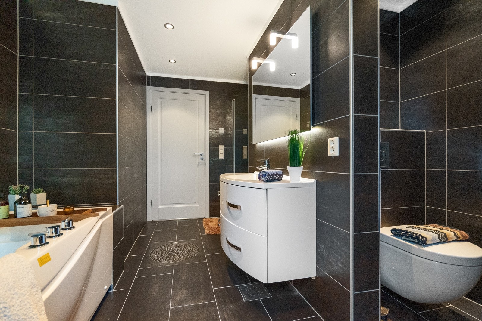 Flislagt bad med baderomsinnredning, dusj, badekar og wc. Galleribilde