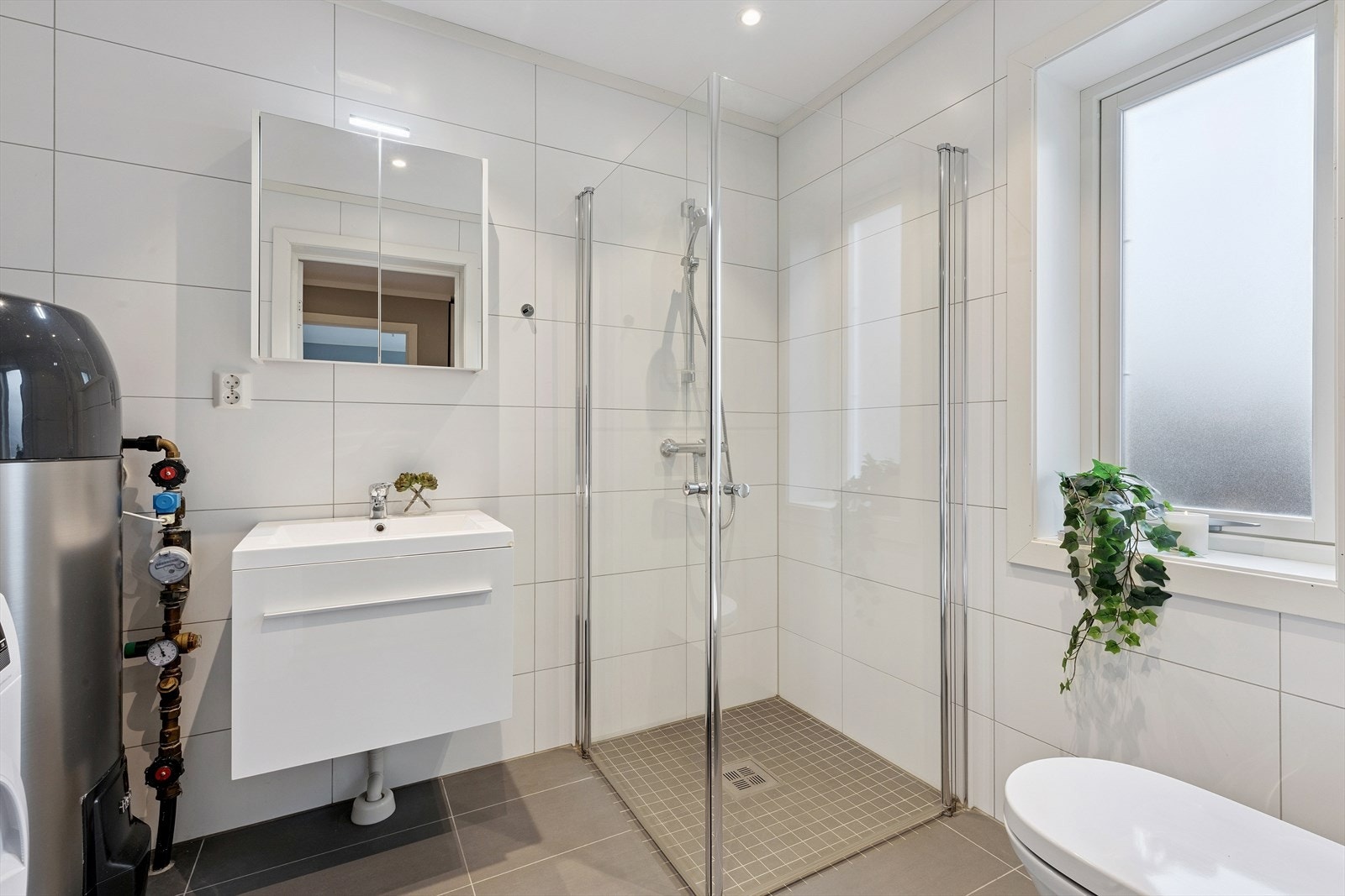 Badet i 1.etasje er et kombinert bad og vaskerom. Varmtvannsberederen er plassert her. Galleribilde