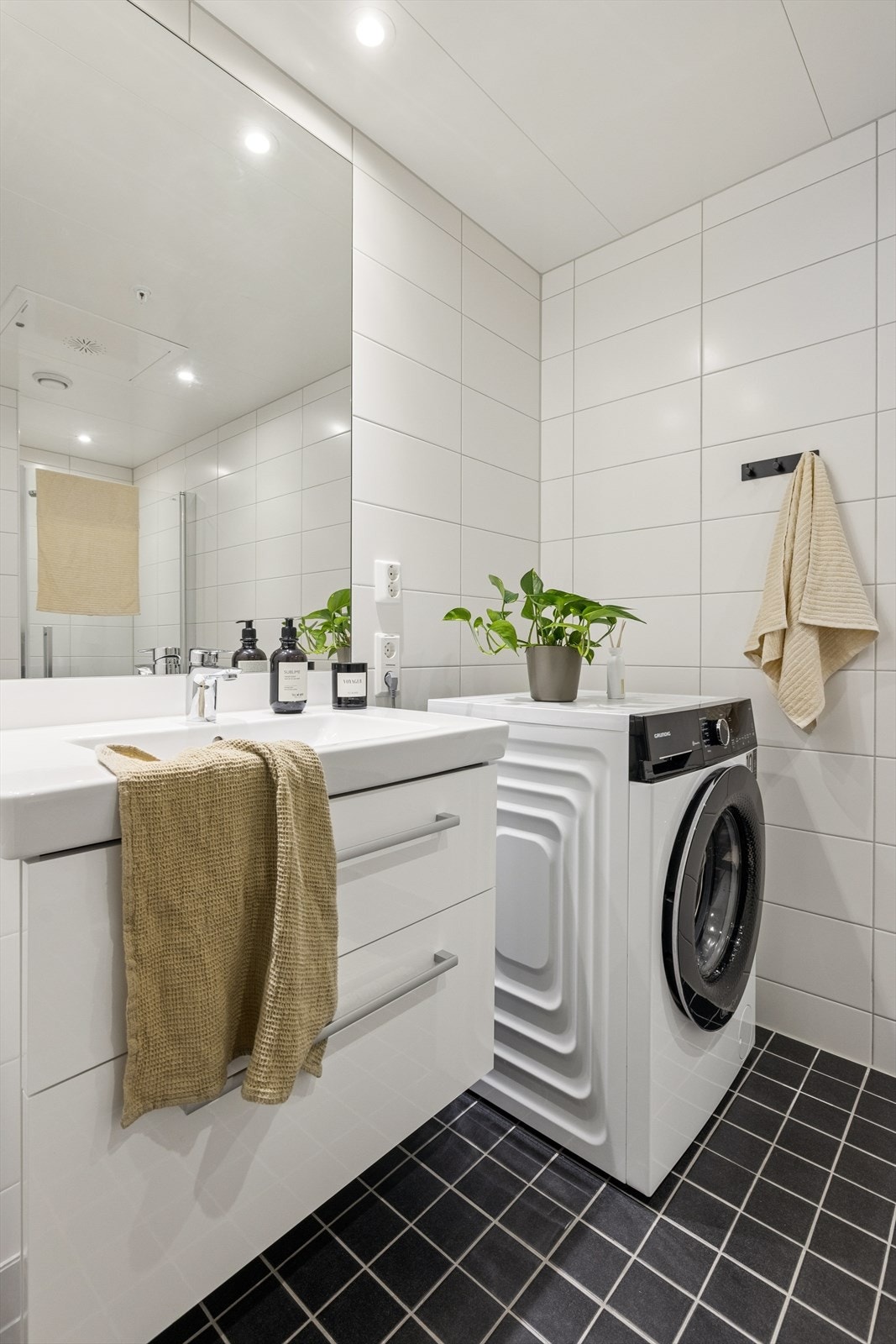 Innredningen består av en baderomsinnredning med skuffseksjon og servant, vegghengt toalett, spotbelysning i taket, opplegg for vaskemaskin og dusjnisje med glassdør. Galleribilde