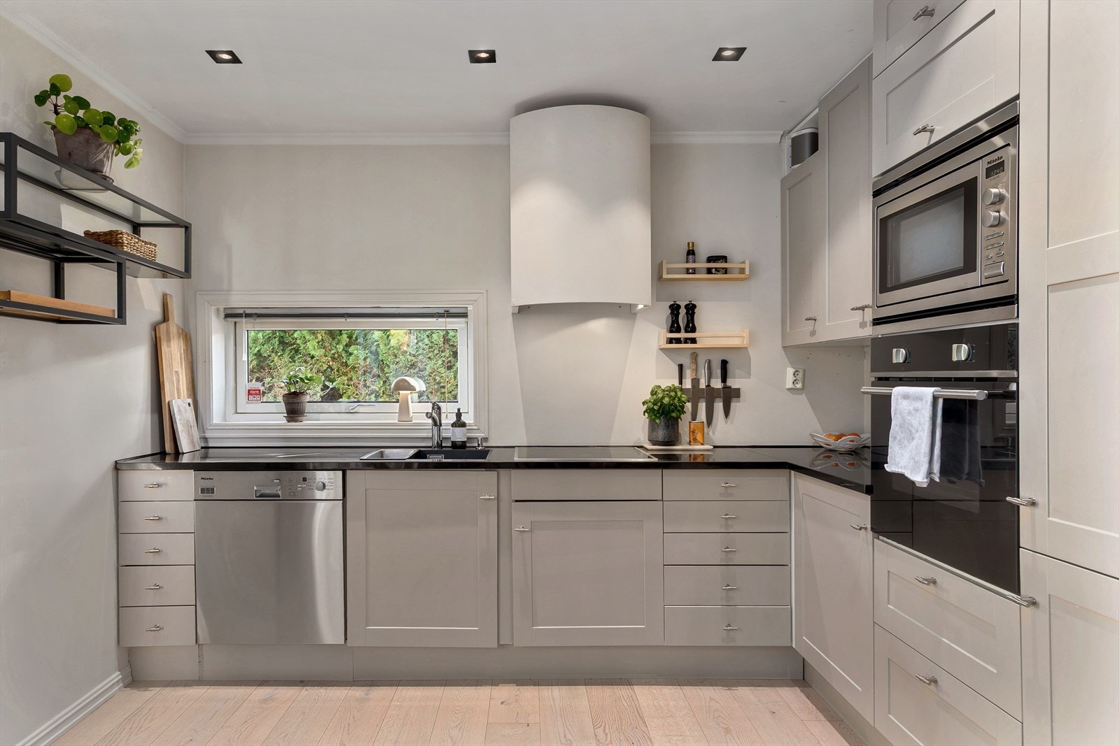 Klassisk og pen kjøkkeninnredning med malte fronter. Polert naturstein benkeplate. Galleribilde